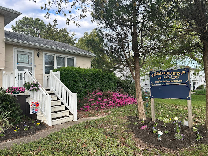 Front yard with house, stairs, bushes, pink flowers, and a sign on a lawn.