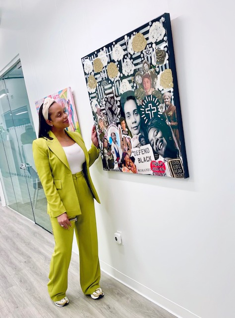 Woman in bright yellow suit standing next to a colorful collage artwork on a white wall.