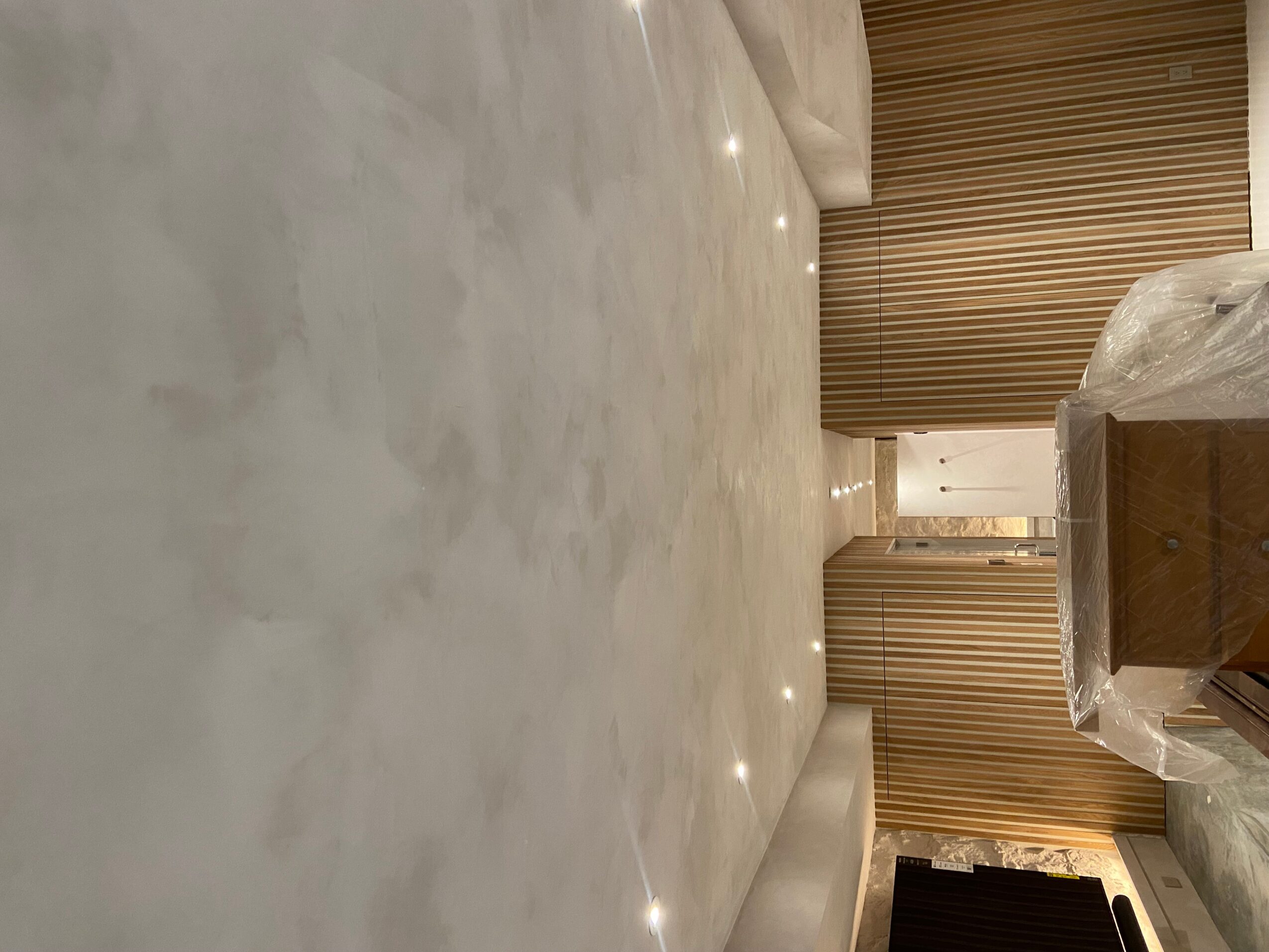 Marble floor with ceiling lights, brown curtains, and a wooden panel wall in a modern interior space.