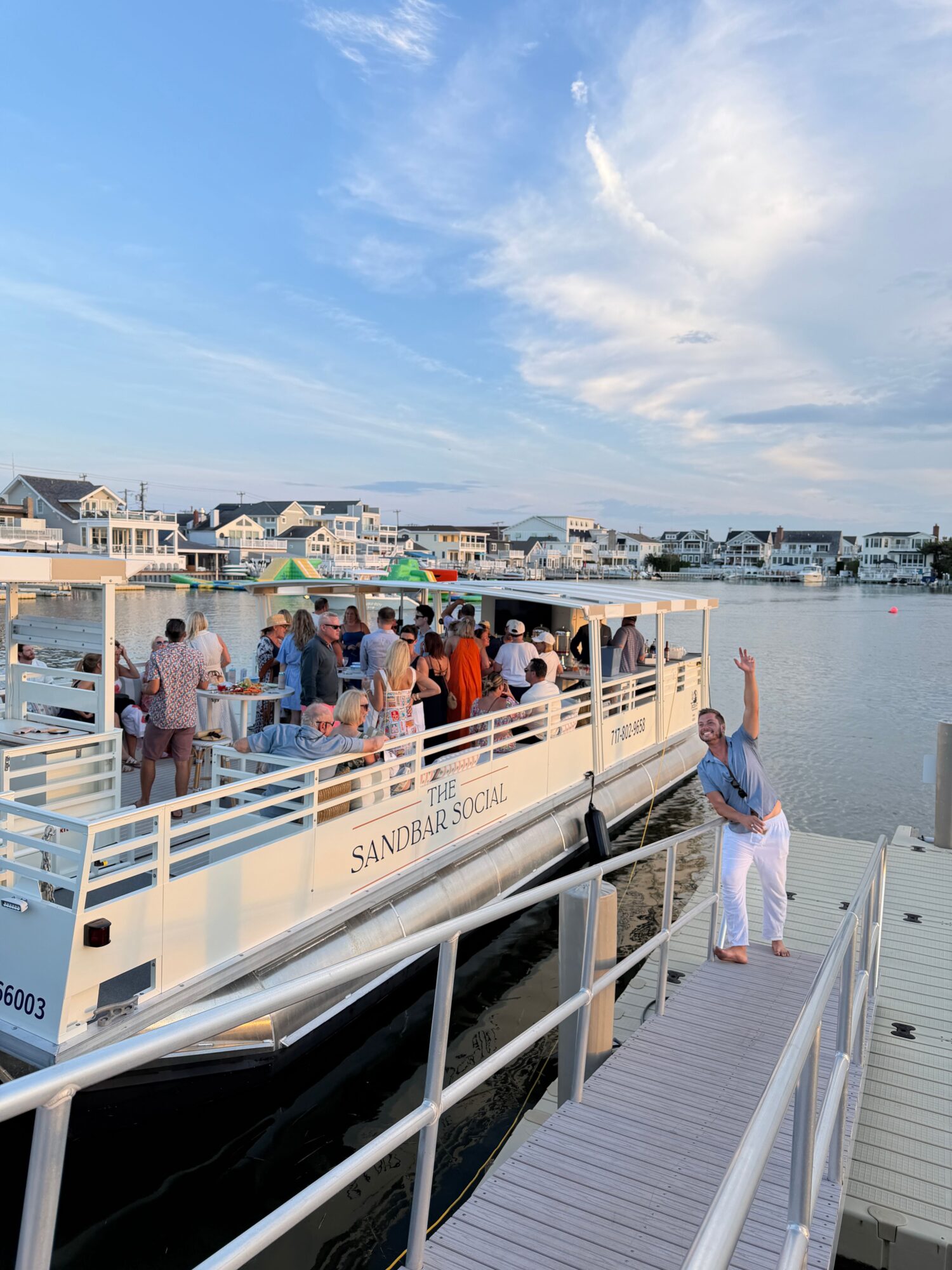 People boarding a boat at a marina with boats and water in the background.