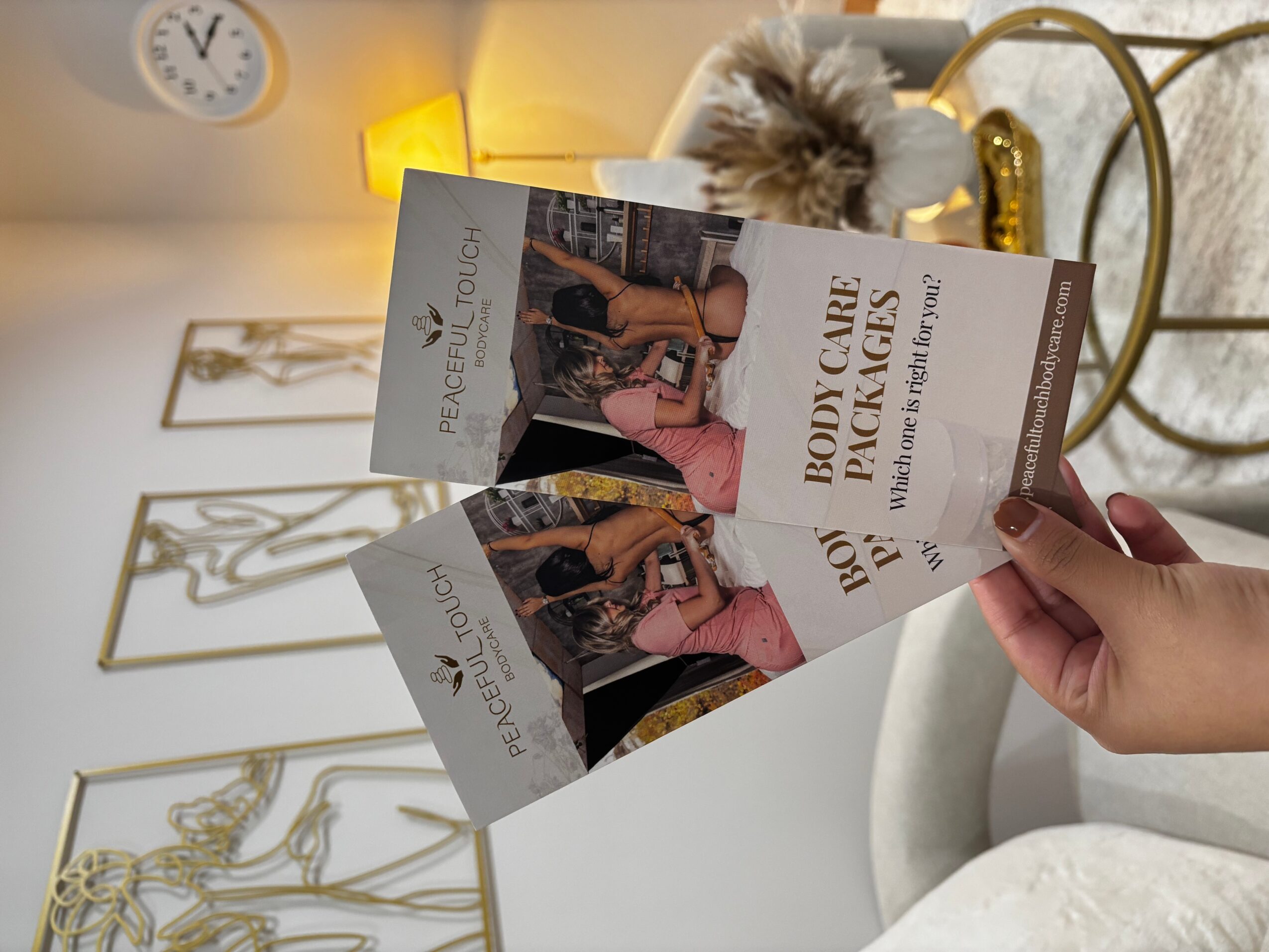 Person holding a book titled 'Body Care Pickles' in a bathroom with gold accents and framed art on the wall.