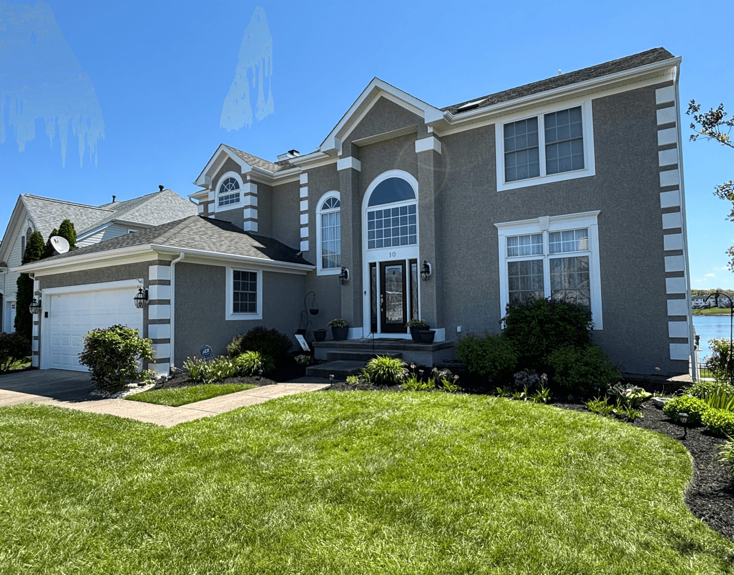 Large two-story house with gray exterior, white trim, front steps, and a well-maintained lawn.