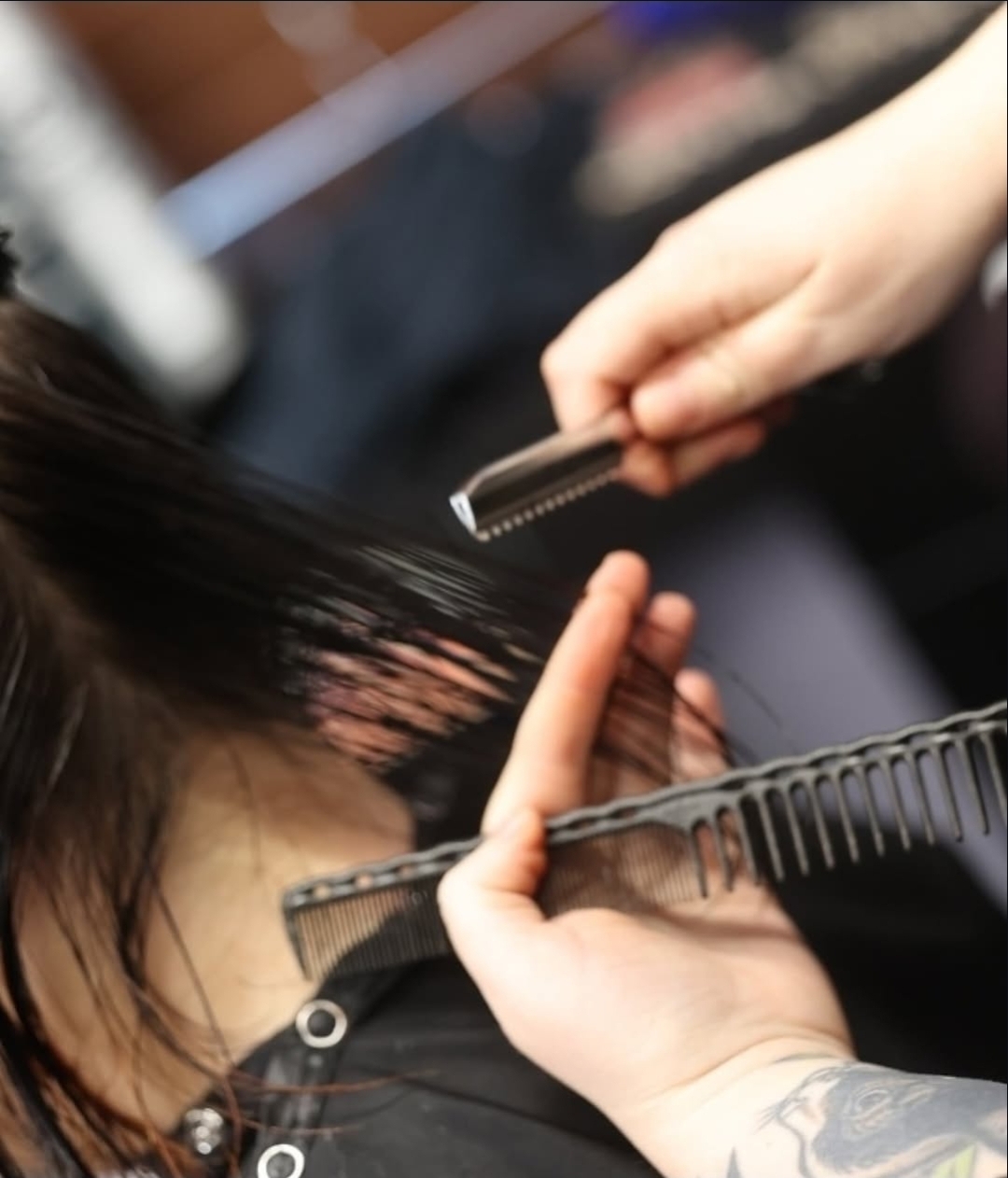 Person getting their hair cut with scissors and a comb, hair being sectioned, in a salon setting.
