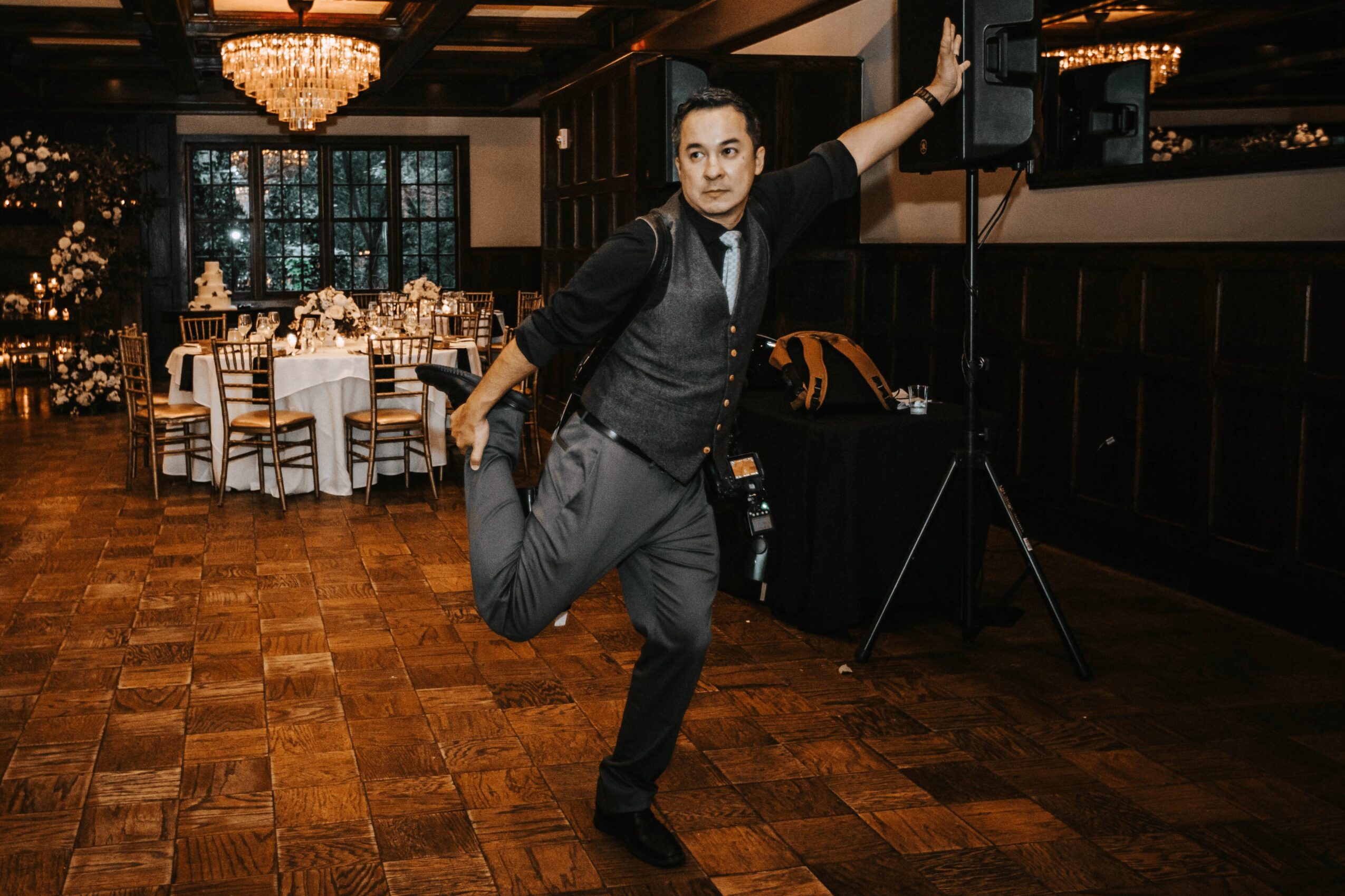Person dancing in formal attire in a decorated event hall with tables and chandeliers