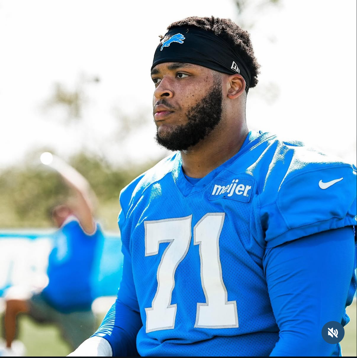 Football player in blue jersey with number 71, wearing a black headband, looking to the side outdoors.