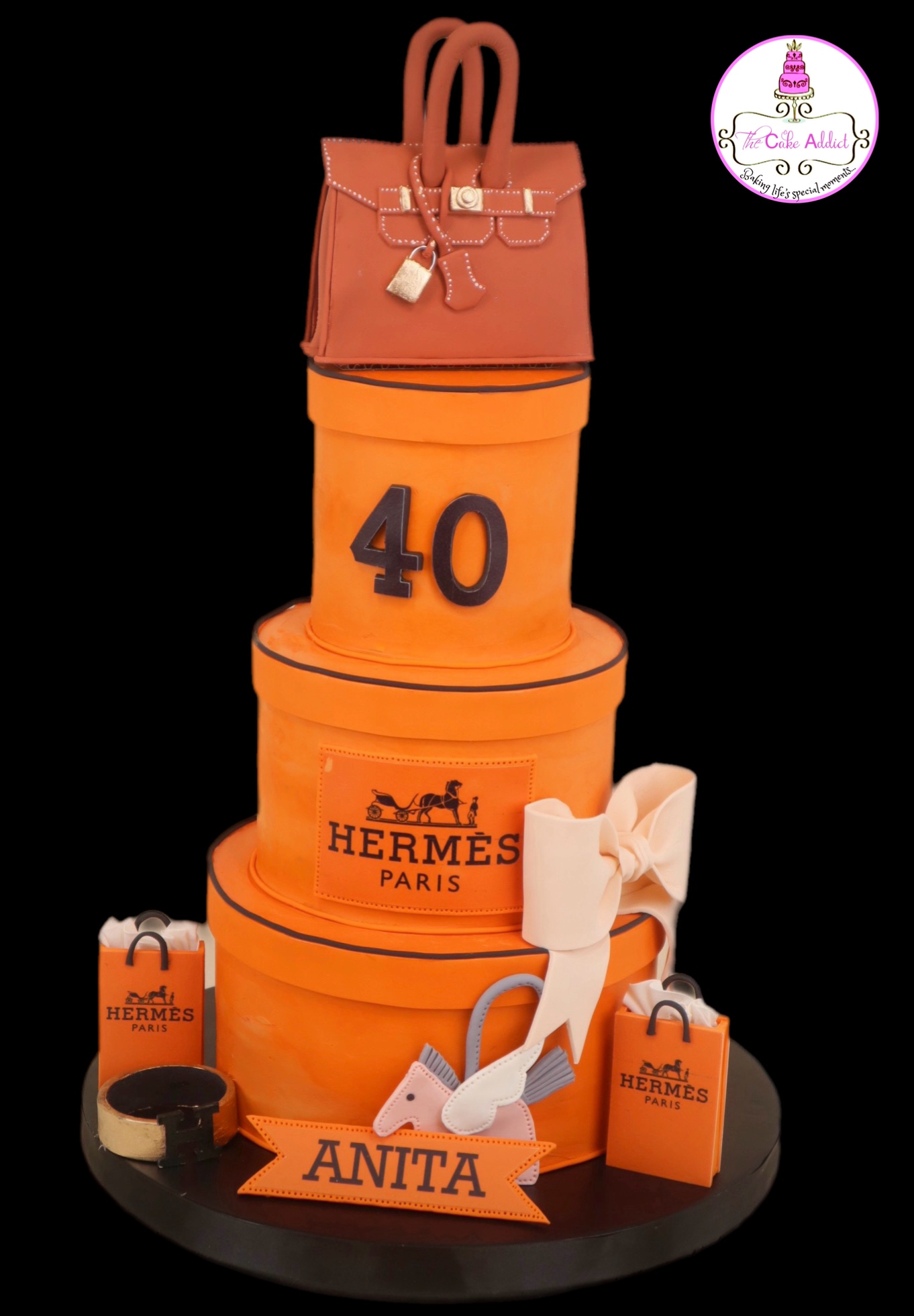 Cake with orange and black Hermes-themed decorations, a handbag on top, and the number 40, with a white bow and shopping bag.