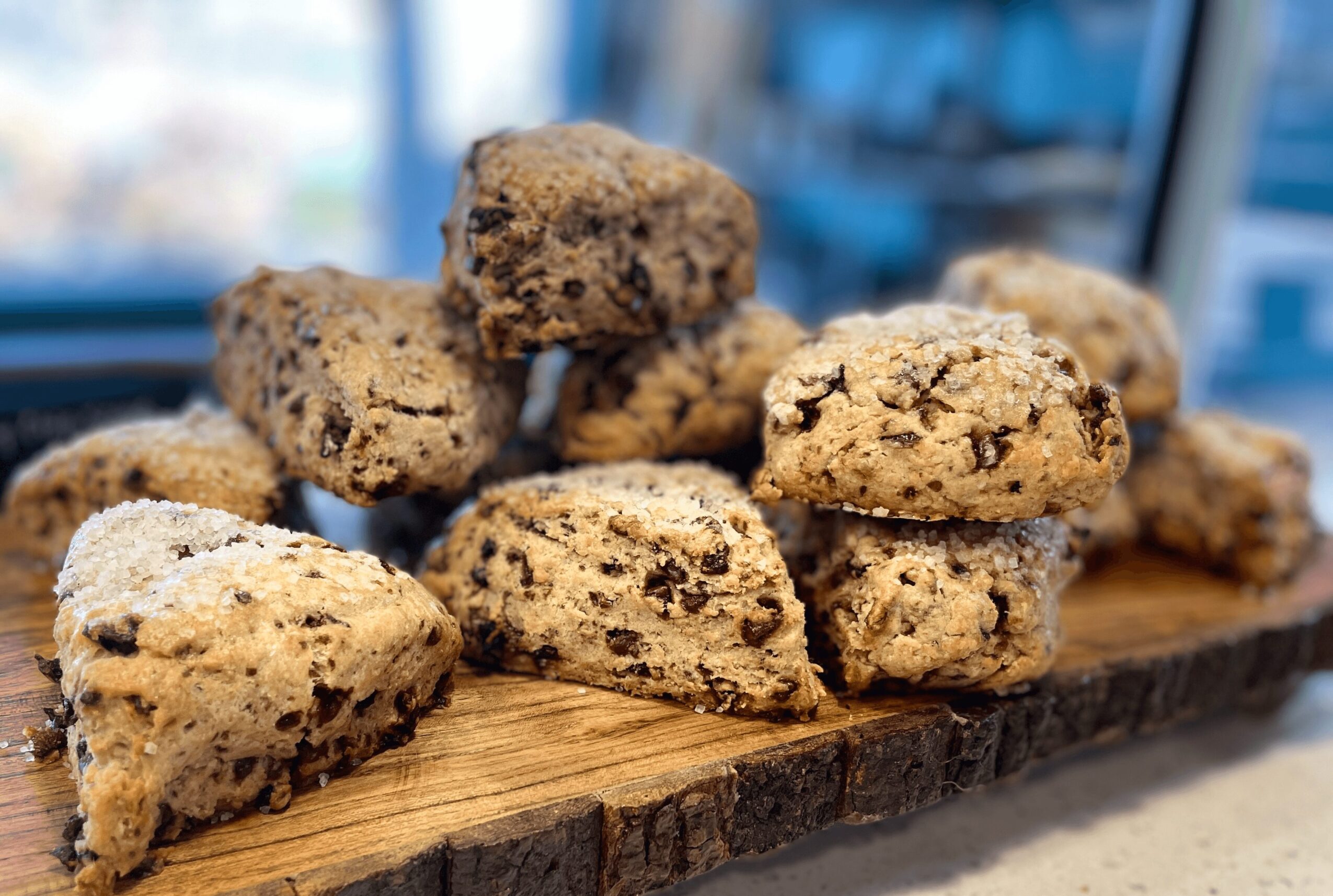 Chocolate chip cookies on a wooden board with a blurred background, some cookies dusted with powdered sugar.