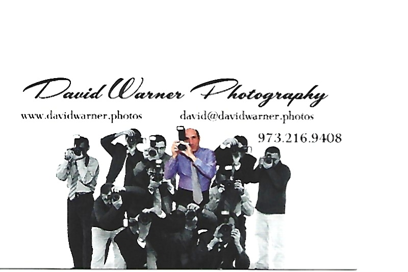 Group of people taking photos, some holding cameras and phones, in a studio setting with a white background.