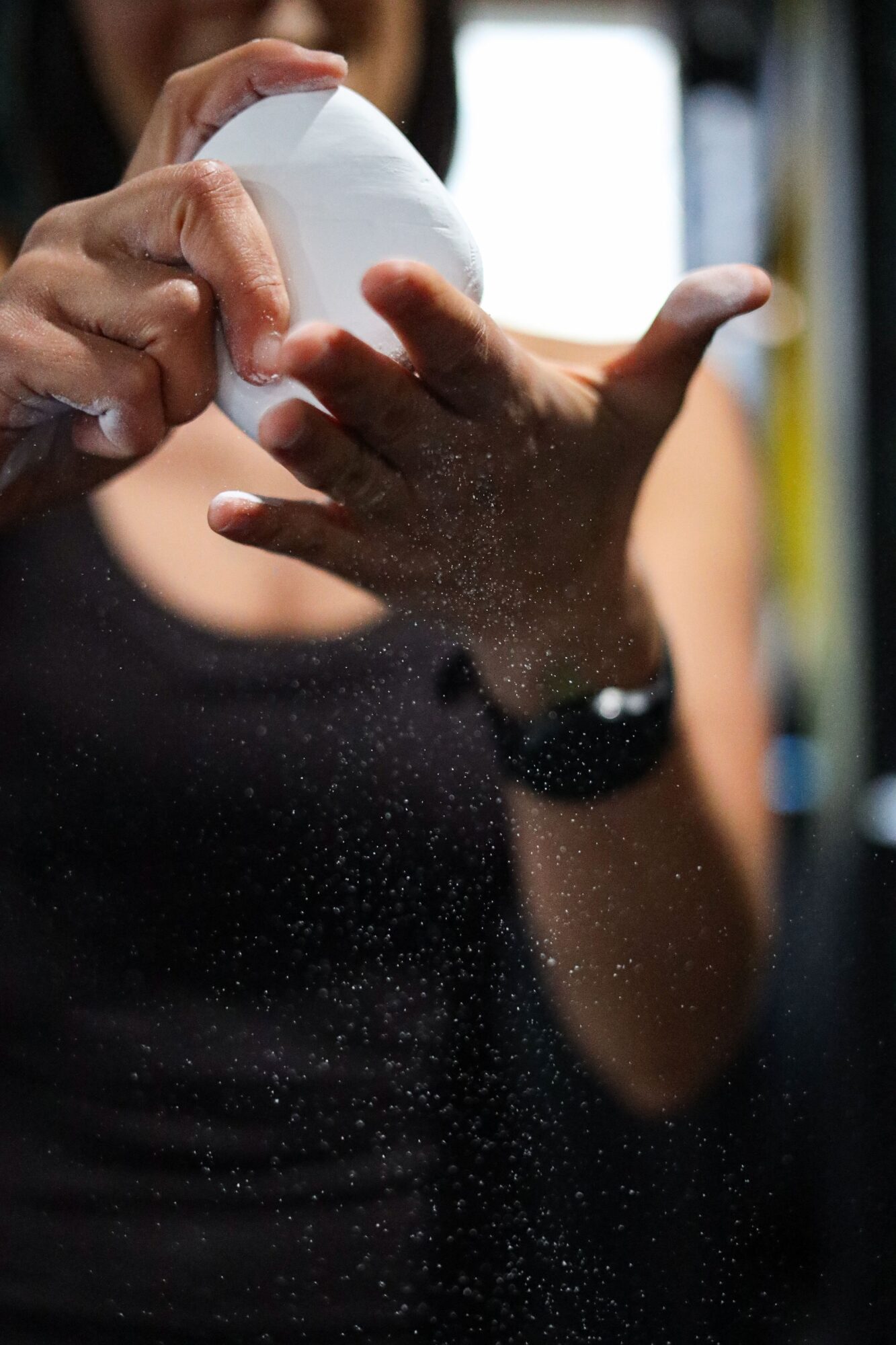 Person pouring powder into their hand, with a blurred background, wearing a black shirt and watch.