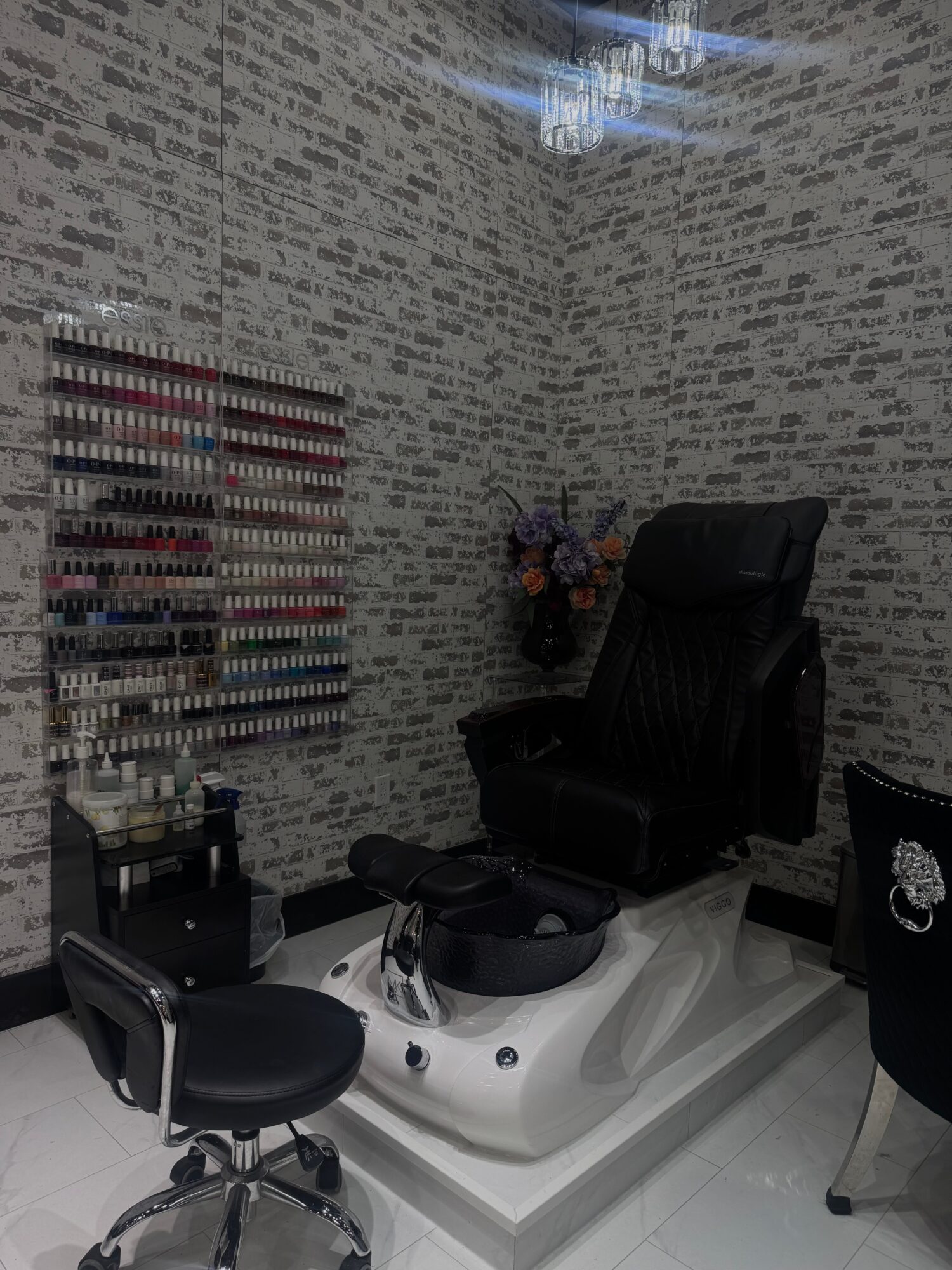 Nail salon with nail polish display, pedicure chair, and flower arrangement in corner.