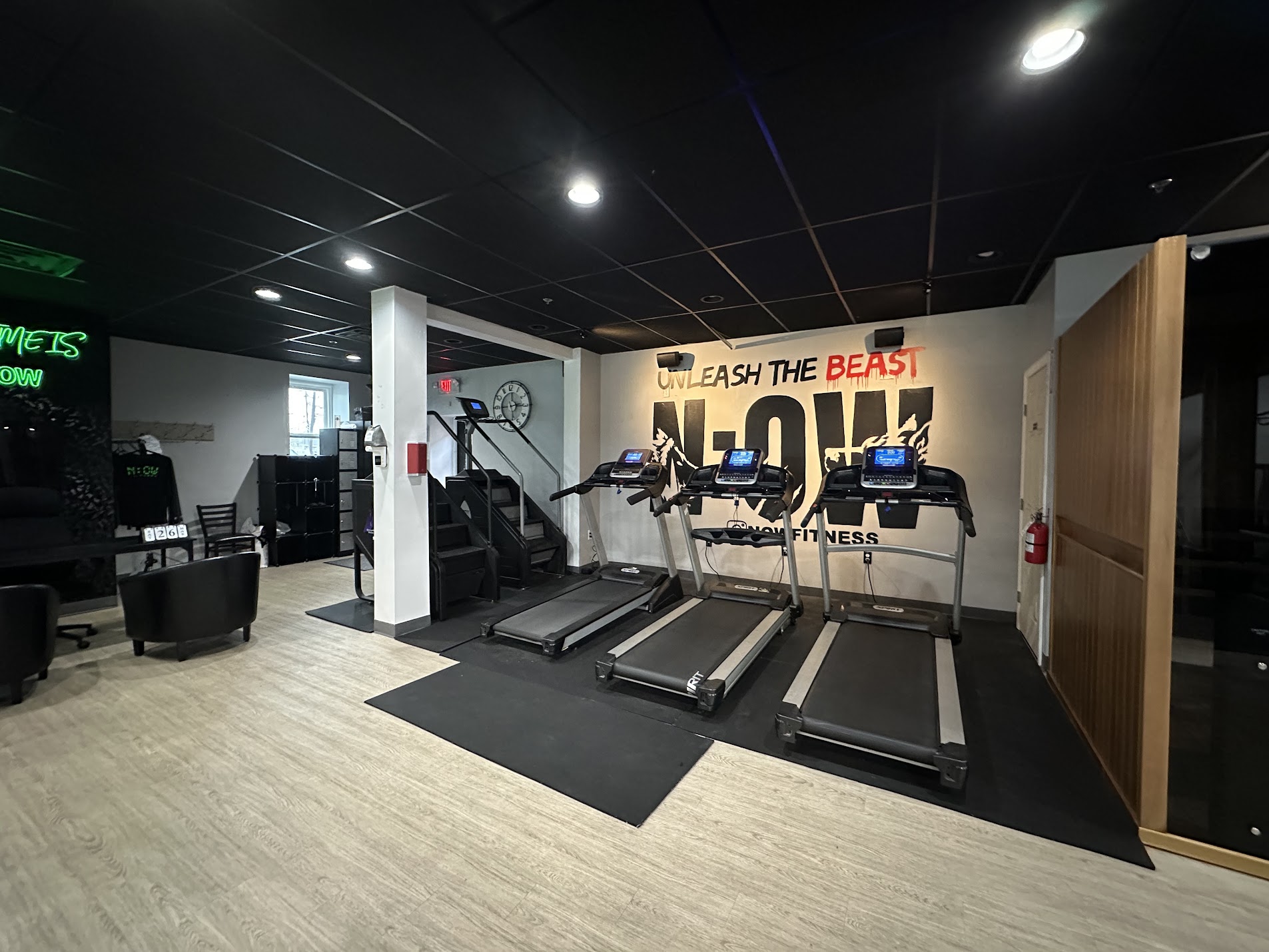 Gym area with three treadmills facing a wall with motivational text, in a modern fitness center.