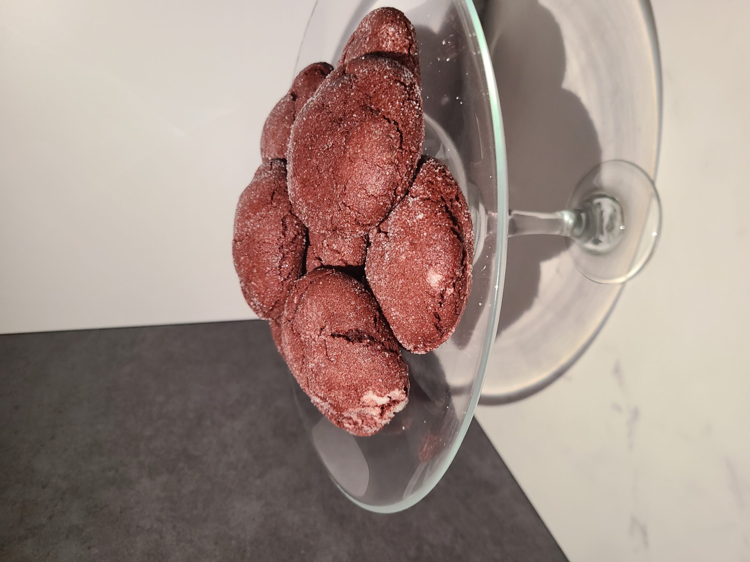 Red frozen strawberries in a glass bowl on a table, viewed from the side.
