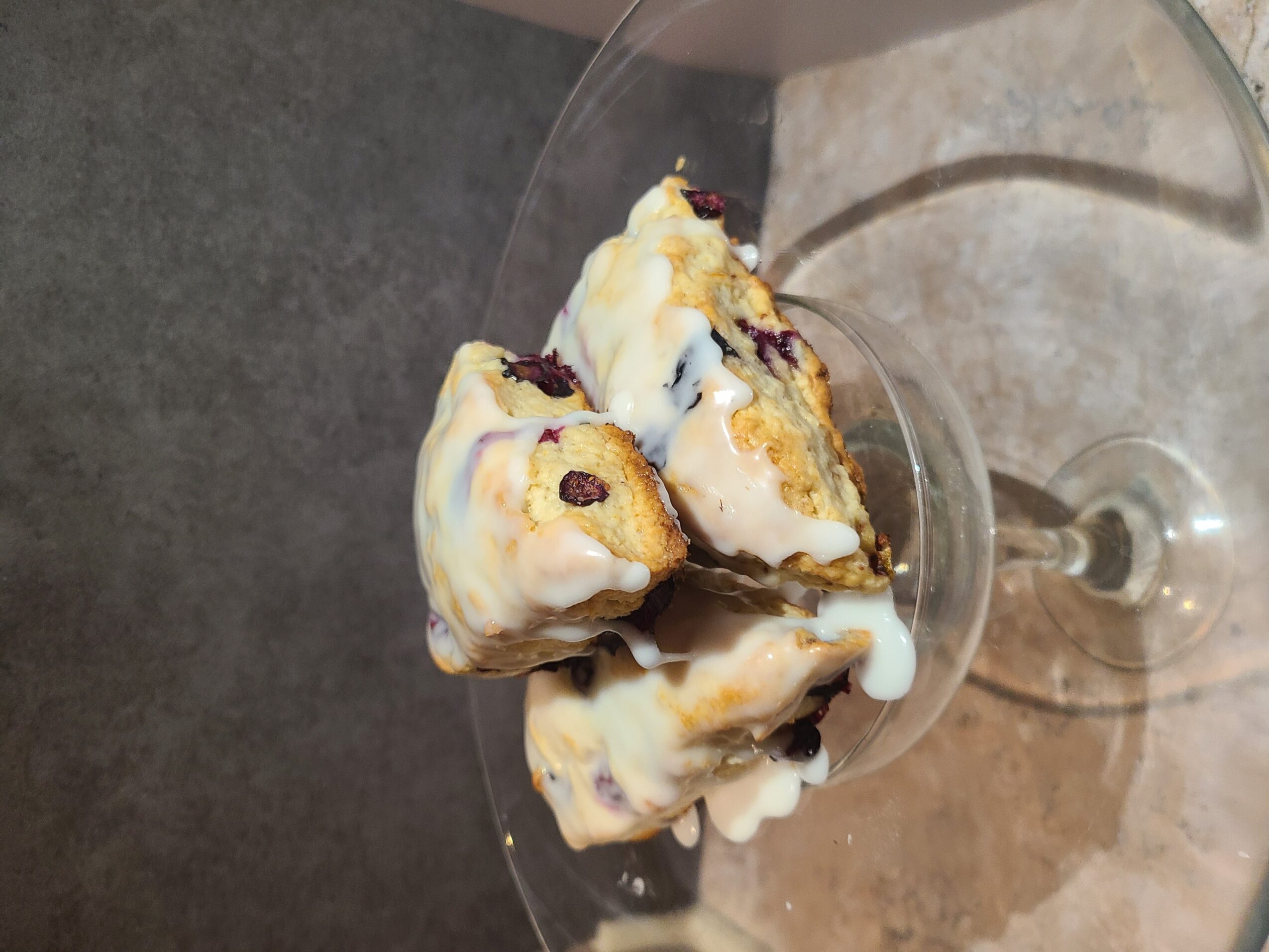Three scoops of ice cream with toppings in a glass bowl on a table, viewed from the side.