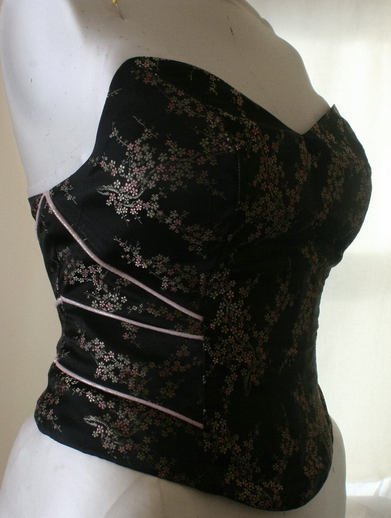 Black strapless dress with floral pattern and white piping details, displayed on a mannequin.