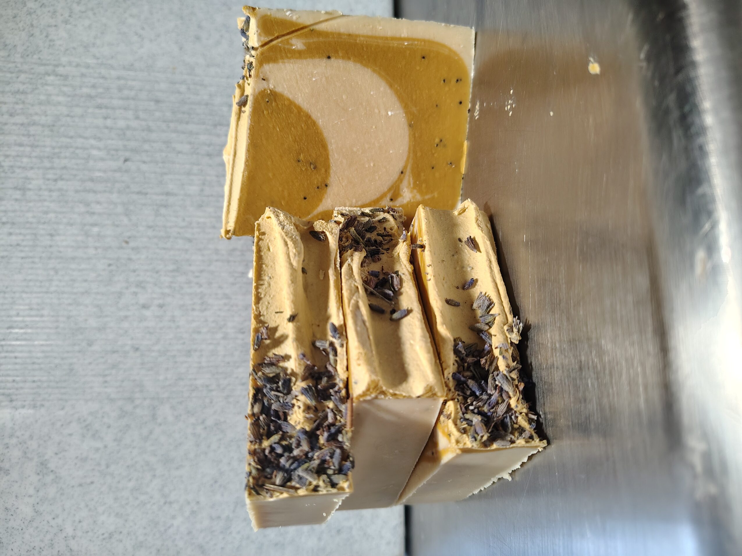 Three ice cream bars with cookie pieces on a metallic surface, one with a swirl pattern on top.