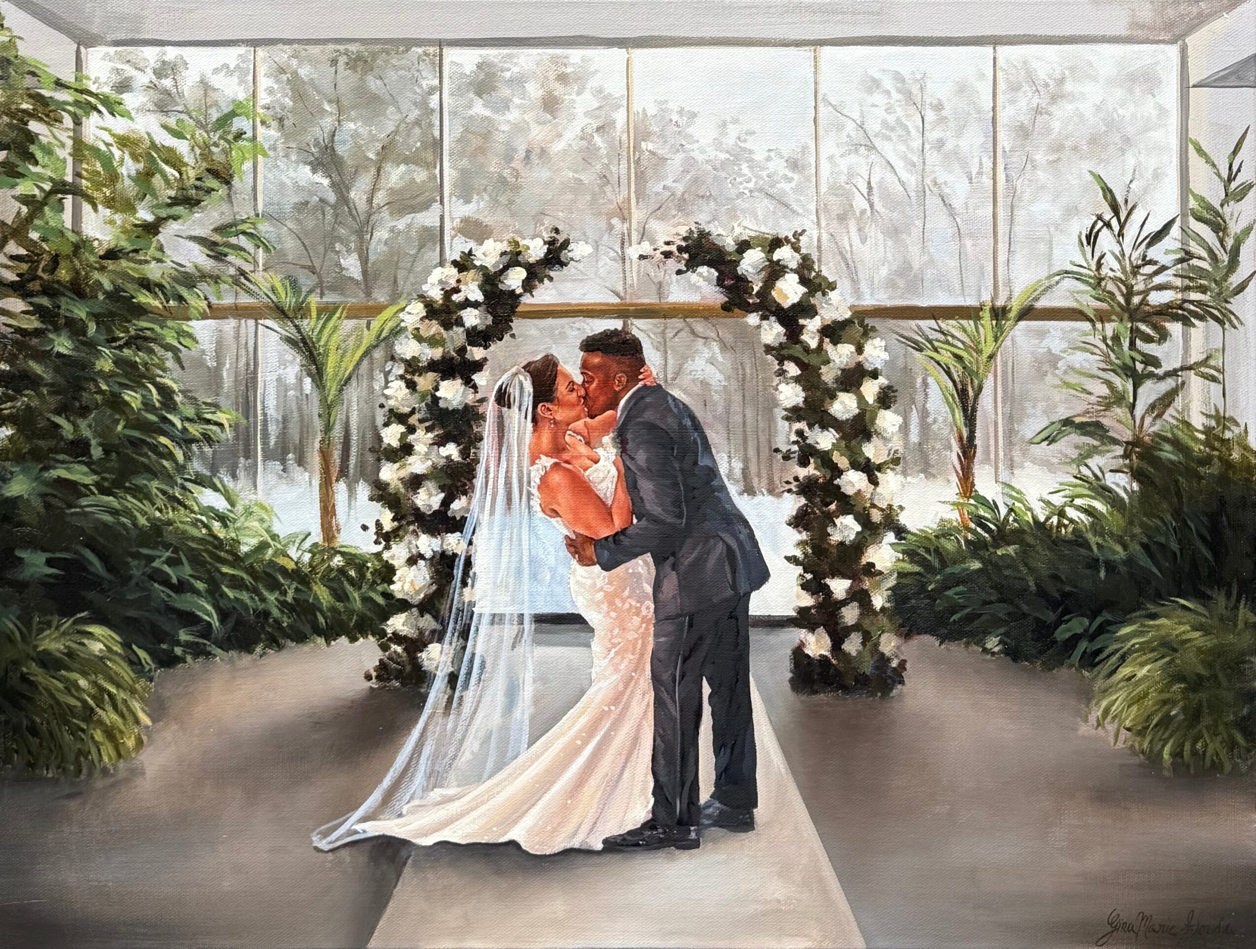 A bride and groom kiss under a floral arch in a bright indoor setting with large windows and greenery.