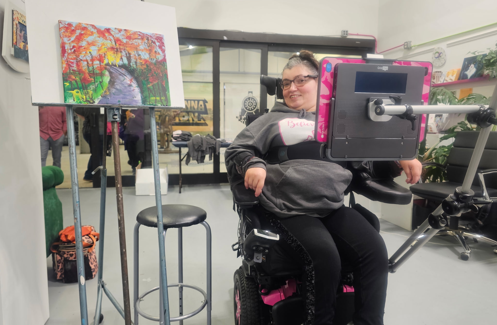 Person in a wheelchair in an art gallery, with colorful paintings and display stands around.