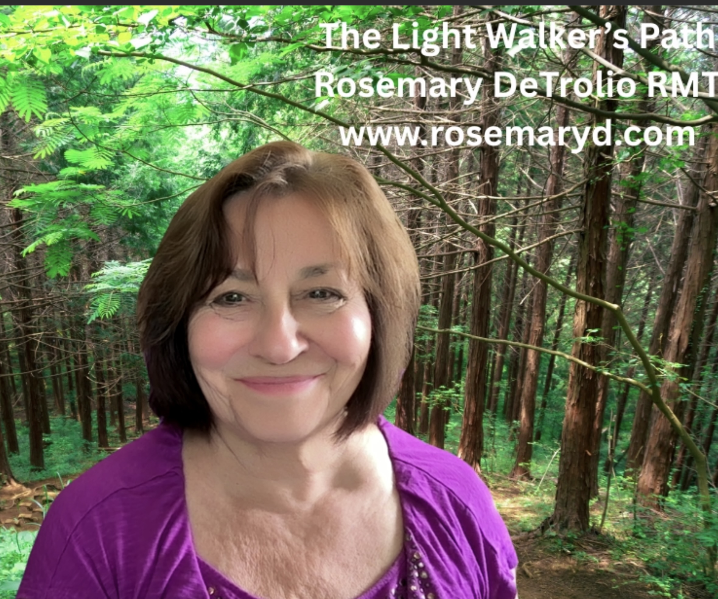 Woman with short brown hair smiling outdoors in a forest, wearing a purple top, with green trees in background.