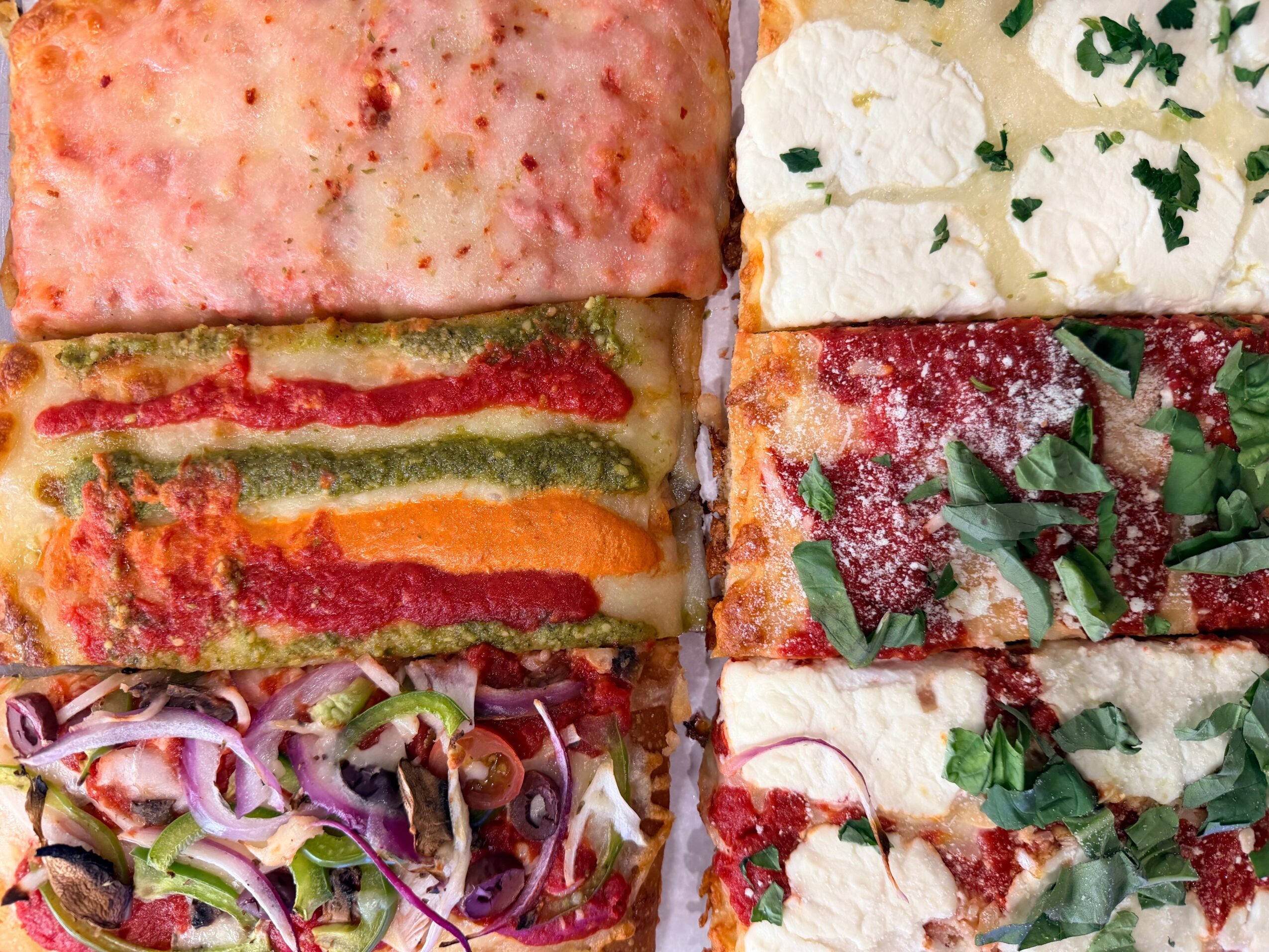 Four slices of layered vegetable and cheese lasagna with tomato sauce, cheese, and herbs, stacked on a plate.