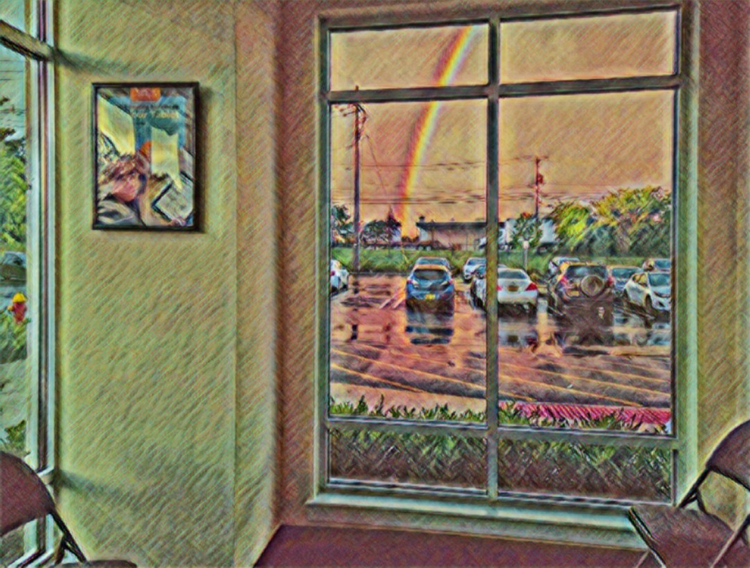 Indoor scene with a large window showing a parking lot and rainbow, framed by green walls and a picture on the wall.