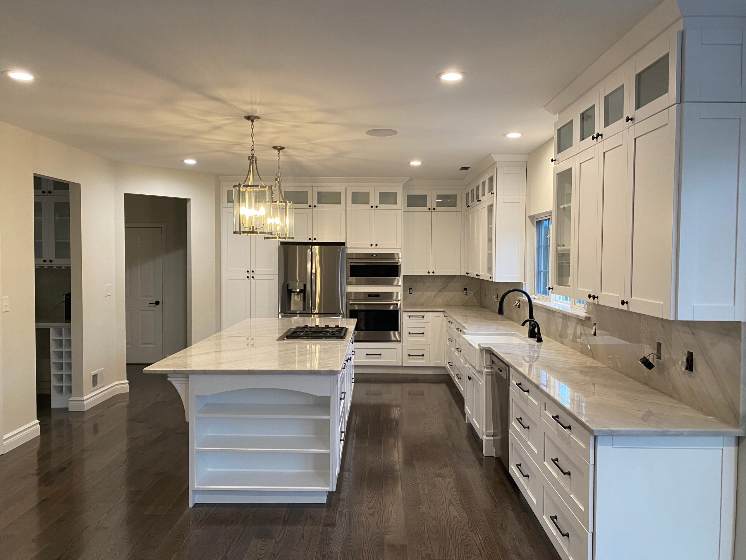 Bright kitchen with white cabinets, island, stainless steel appliances, and dark hardwood floors.