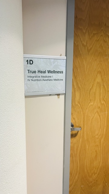 Wooden door with a silver handle and a sign reading '1D True Heal Wellness Integrative Medicine.'