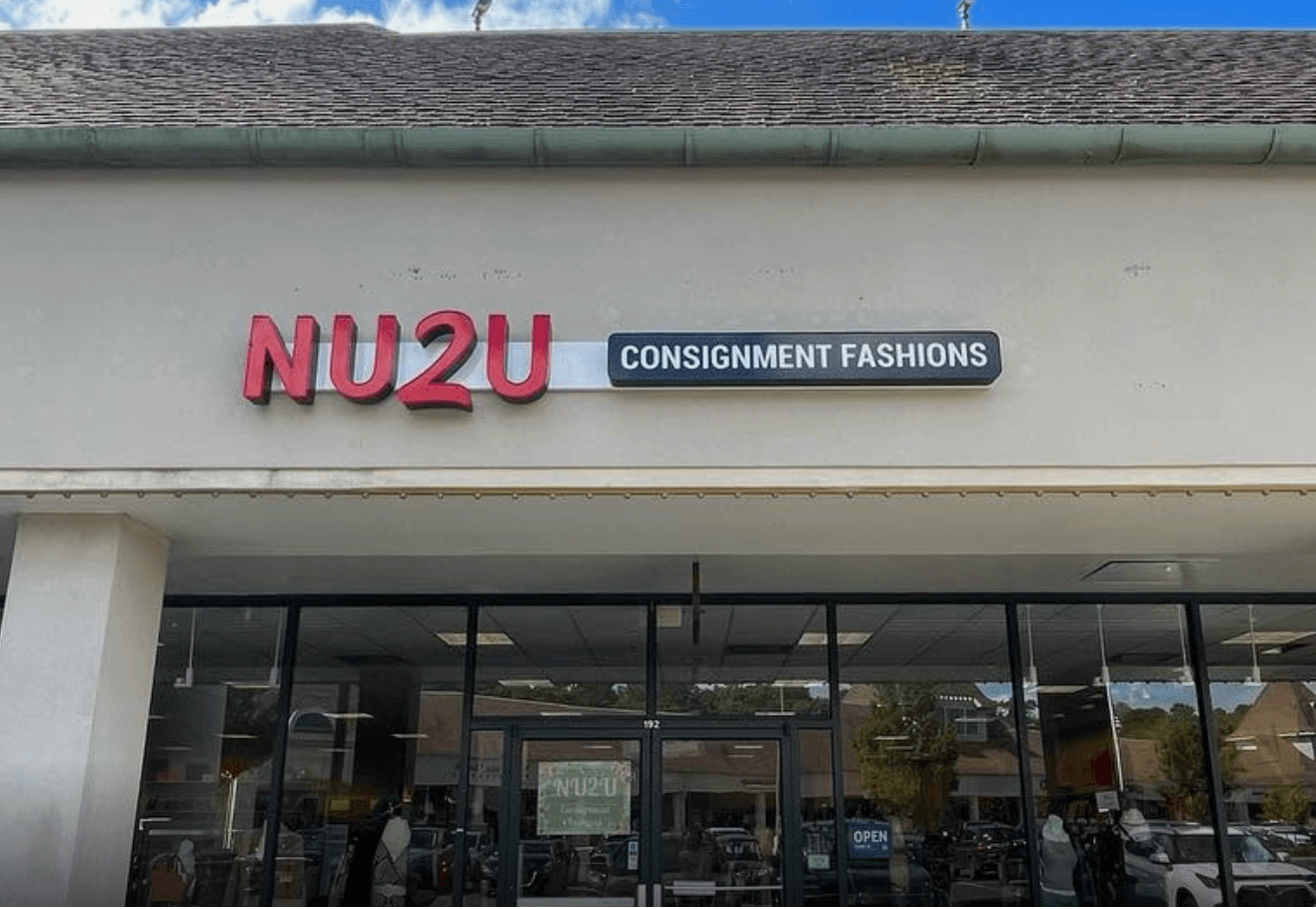 Storefront with sign reading 'NUZU' and a smaller sign 'CONSIGNMENT FASHIONS' above glass windows.
