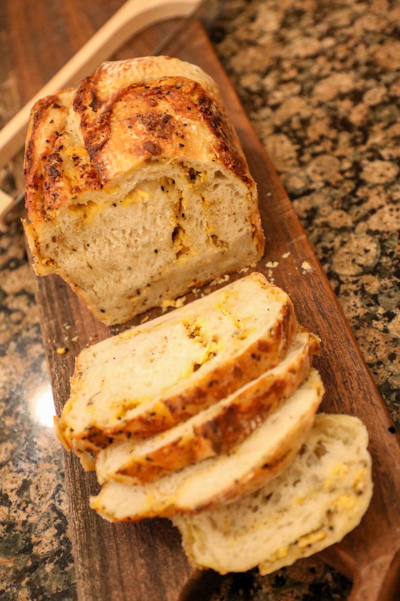Slices of swirled bread on a wooden serving board, with a marble countertop background.