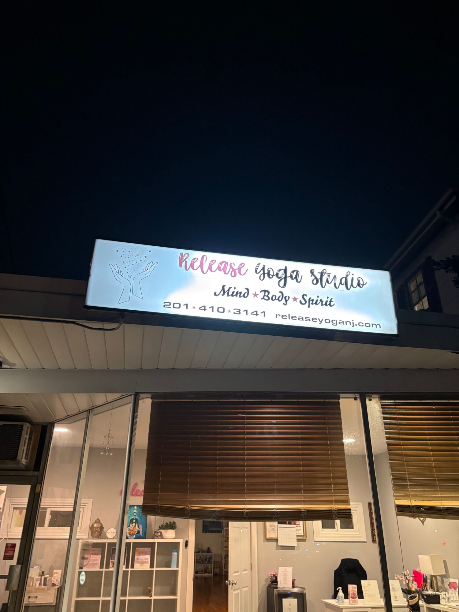 Storefront with a large window and a signboard outside, illuminated at night.