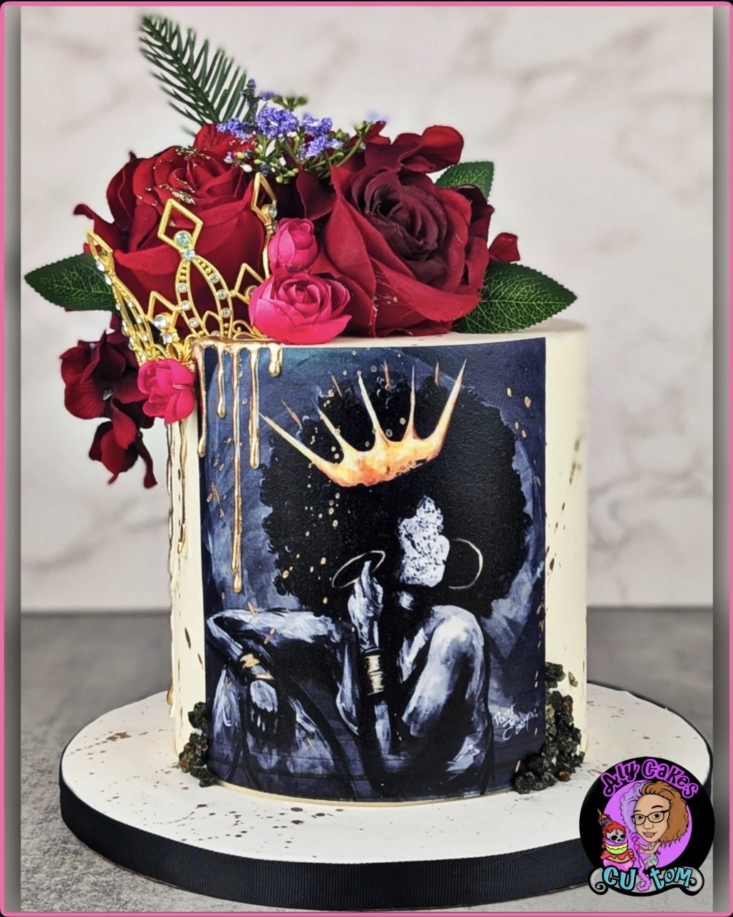 Cake with a painted portrait of a woman wearing a crown, decorated with red and pink roses and greenery, on a white marble background.