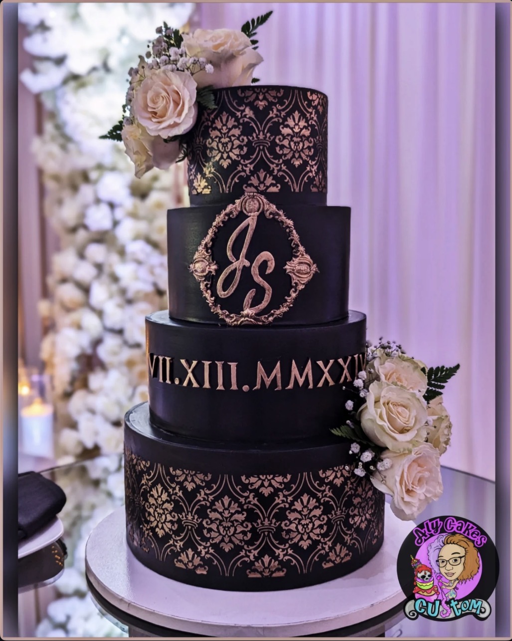 Three-tiered black wedding cake with pink floral decorations and Roman numerals, decorated with roses and lace patterns.