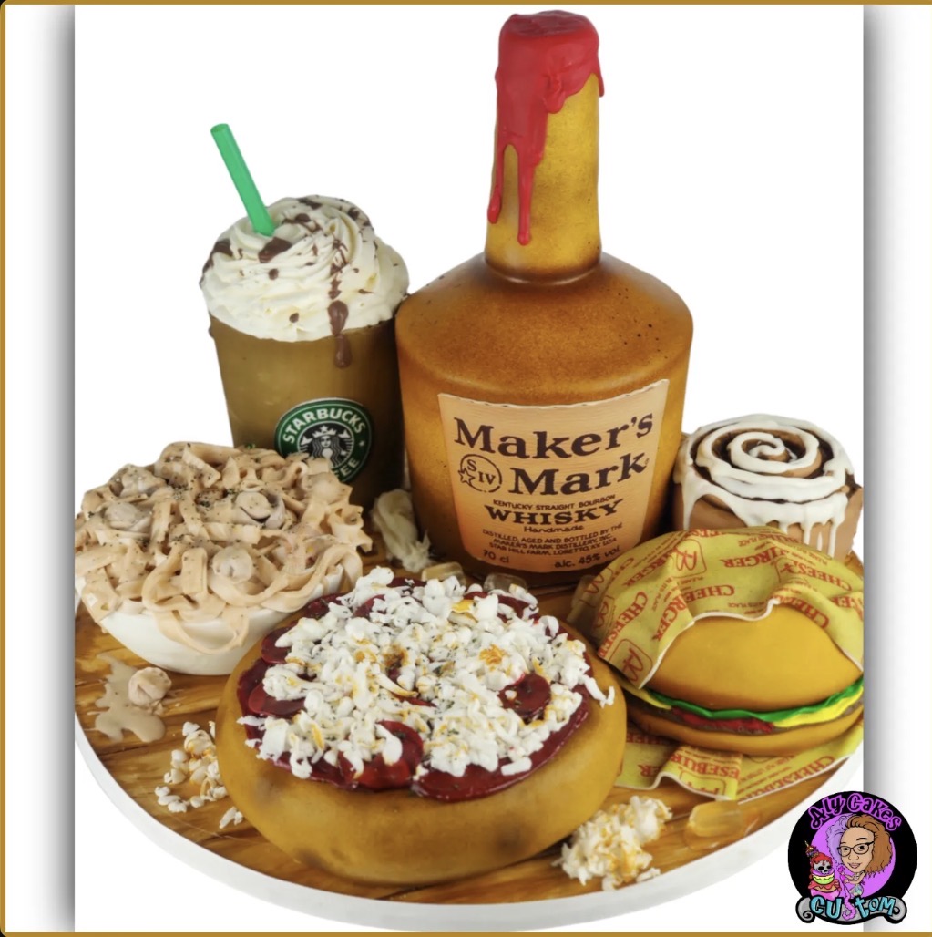 Plate with a frappuccino, whiskey bottle, cinnamon roll, donut with frosting, and a wrapped snack, all on a white surface.