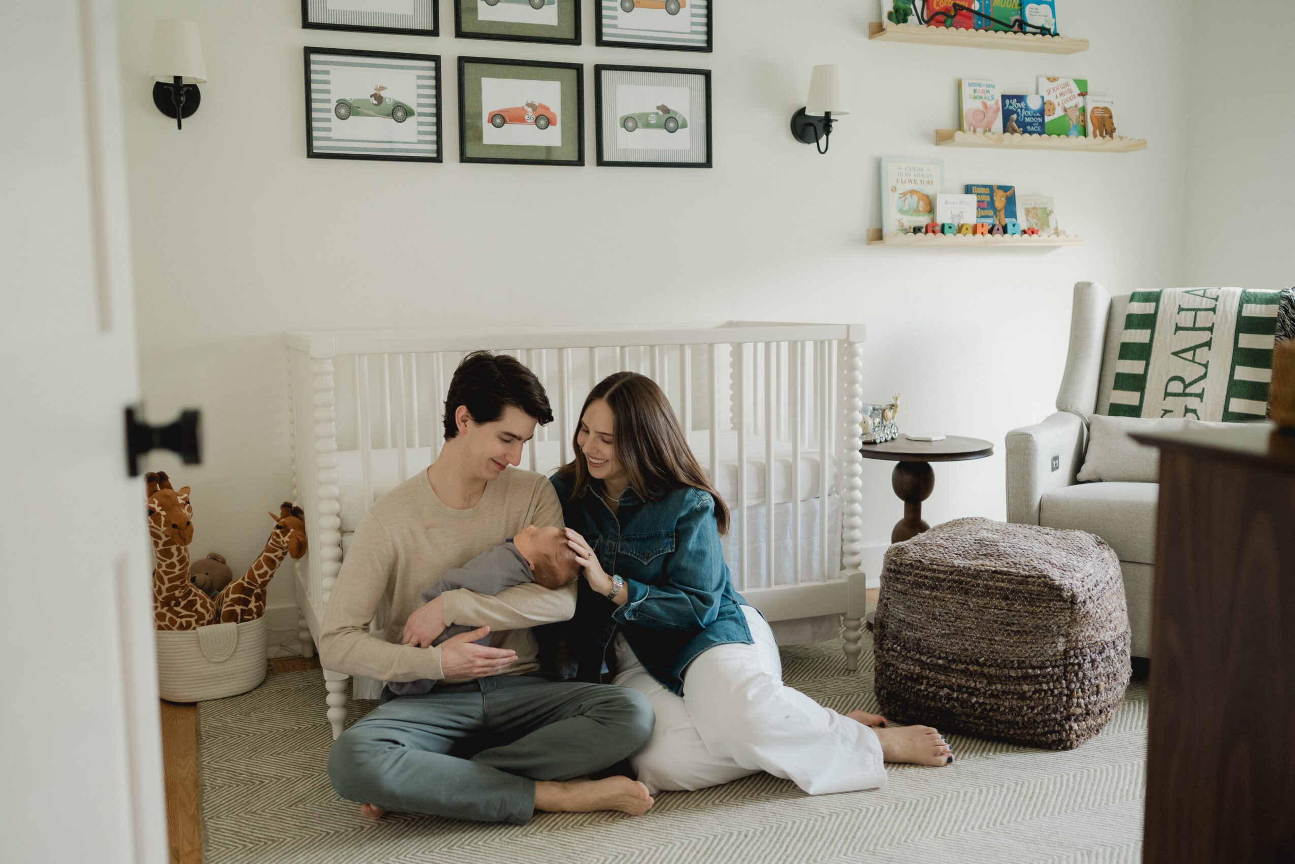 Two people sit on the floor in a living room, looking at a tablet together, with a child nearby and decorative items around.