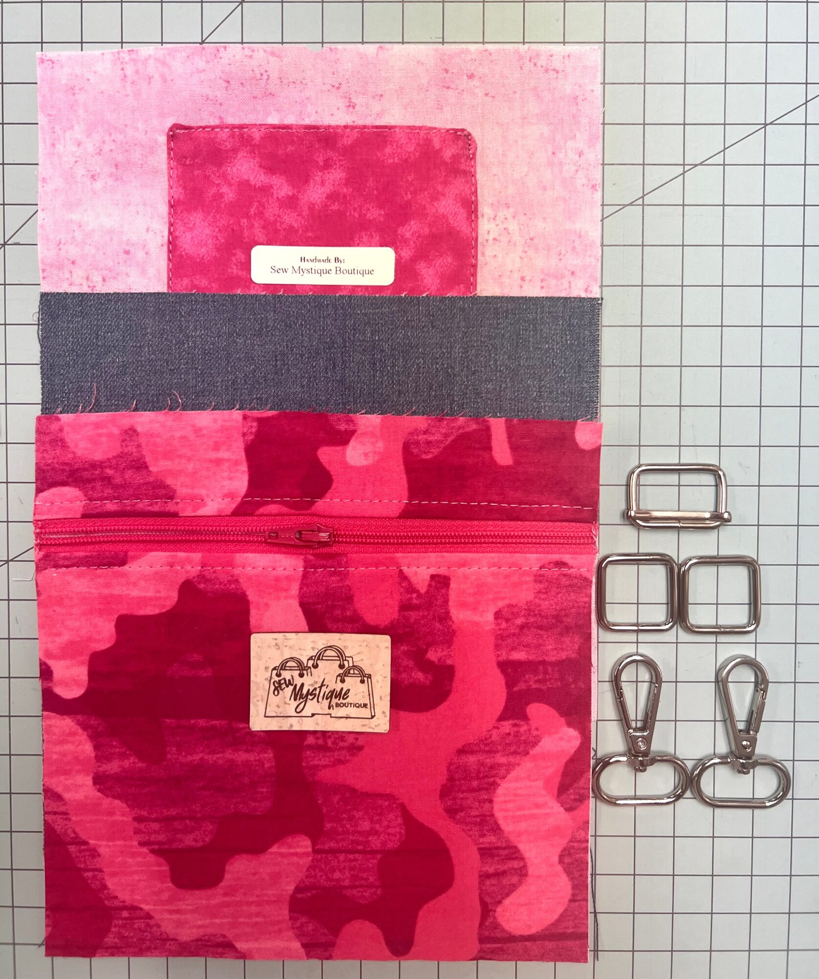 Pink fabric organizer with pockets and label, alongside six metal clips on a grid background.