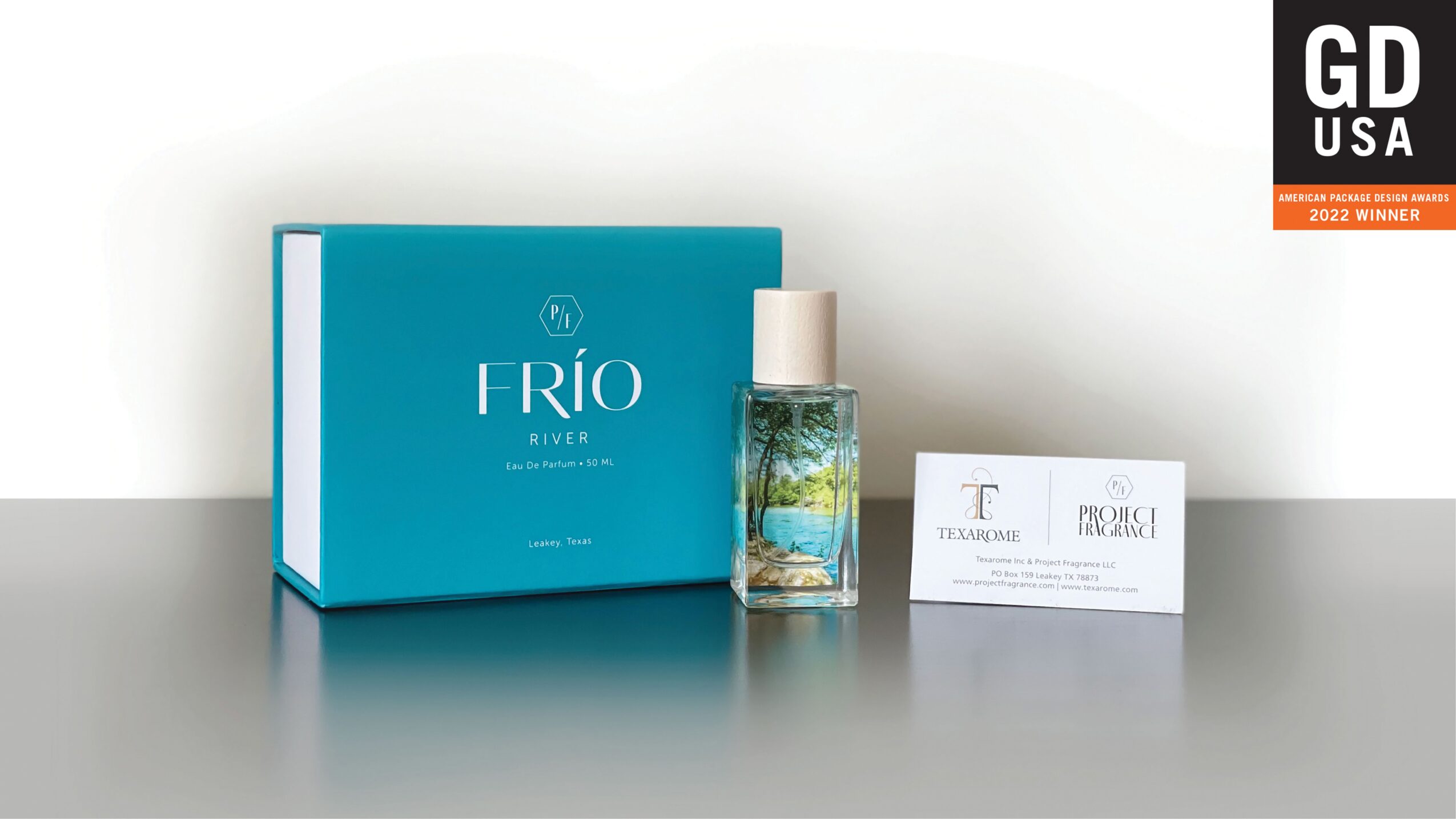 A blue box labeled 'TRIO' with a glass bottle and a white card beside it on a gray surface.