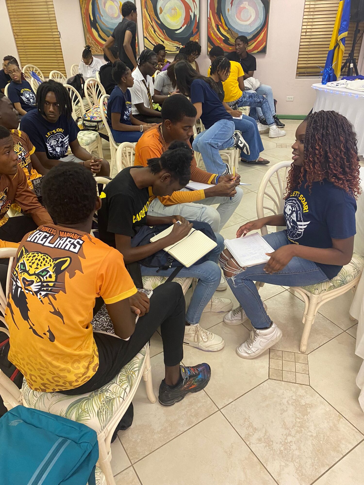 Group of young people sitting and talking in a room with colorful artwork on the walls.