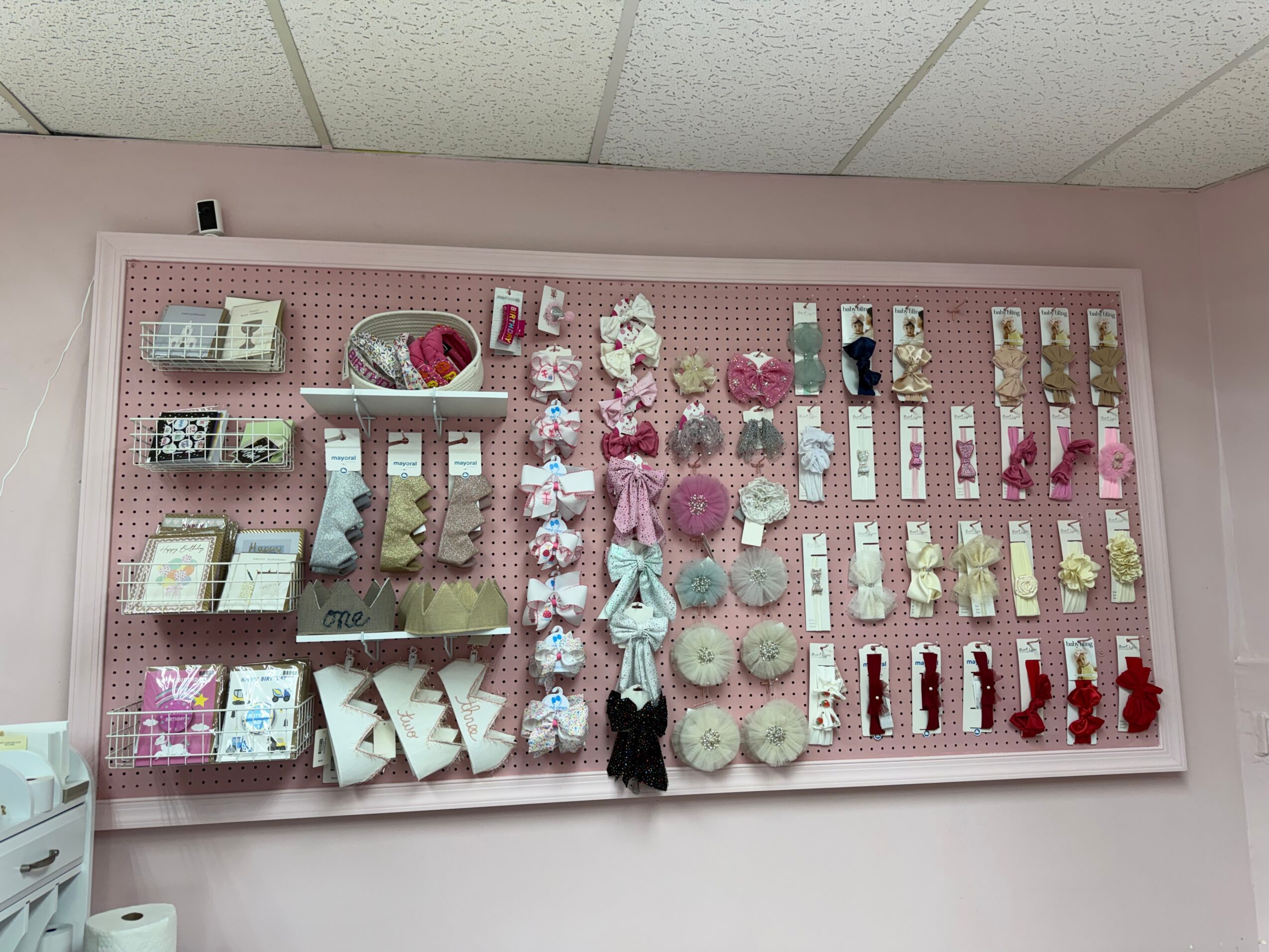 Pink pegboard wall with various decorative items, including socks, plush toys, and accessories, arranged in rows and sections.