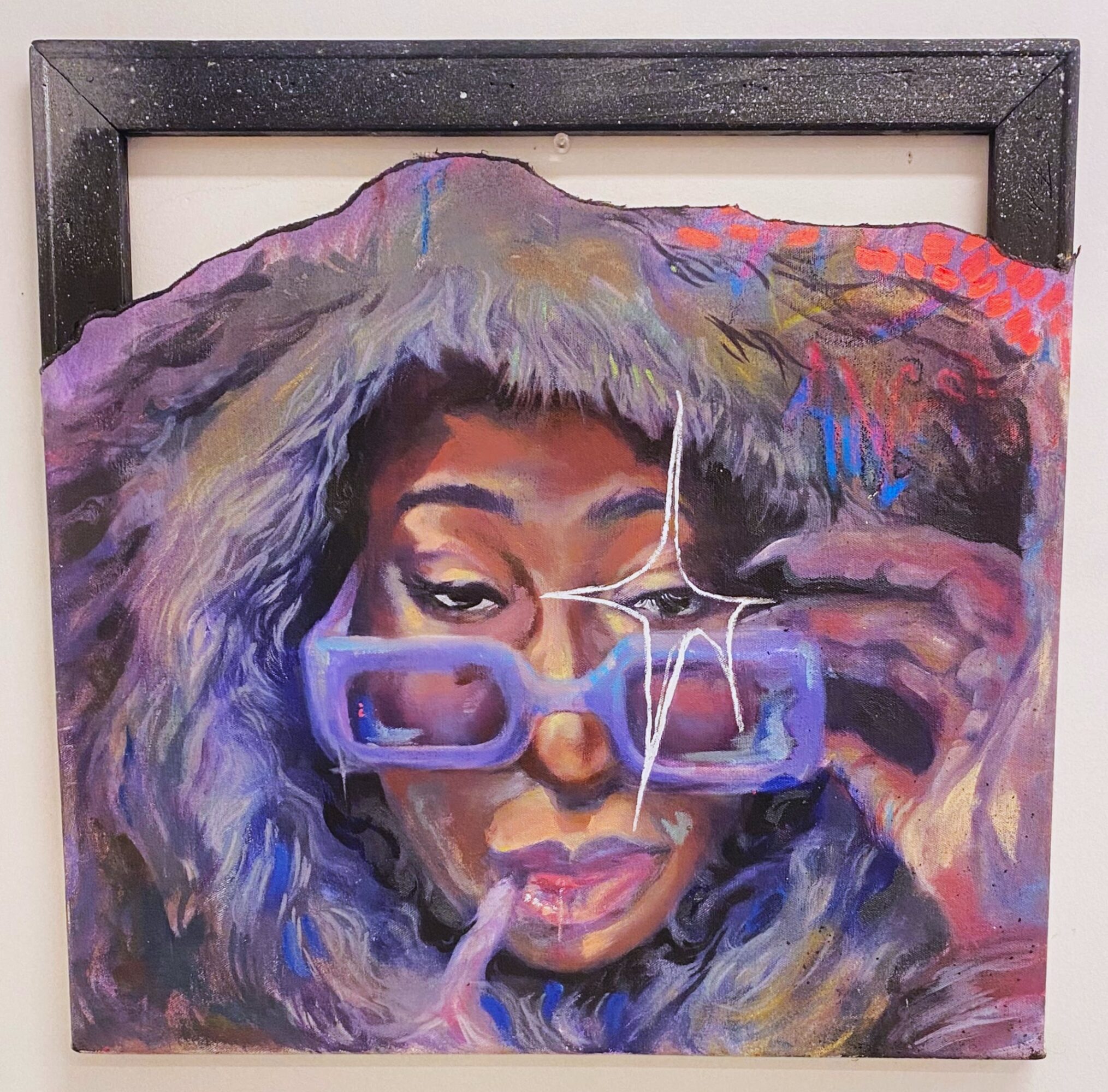 Portrait of a woman with colorful hair, wearing glasses, holding a strand of hair, with a neutral expression.