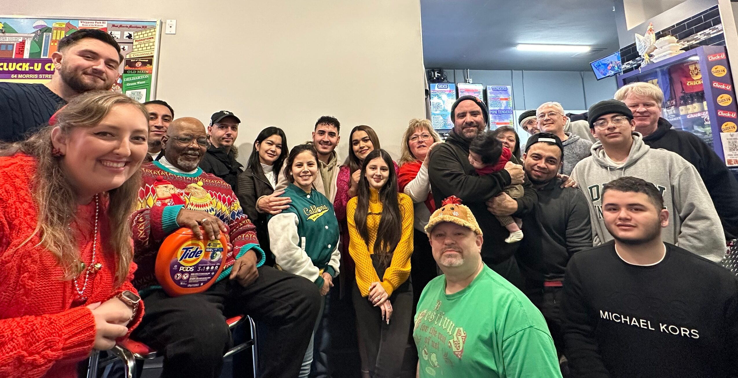 Group of people smiling indoors, some holding a colorful ball, in a casual setting with gaming machines in background.