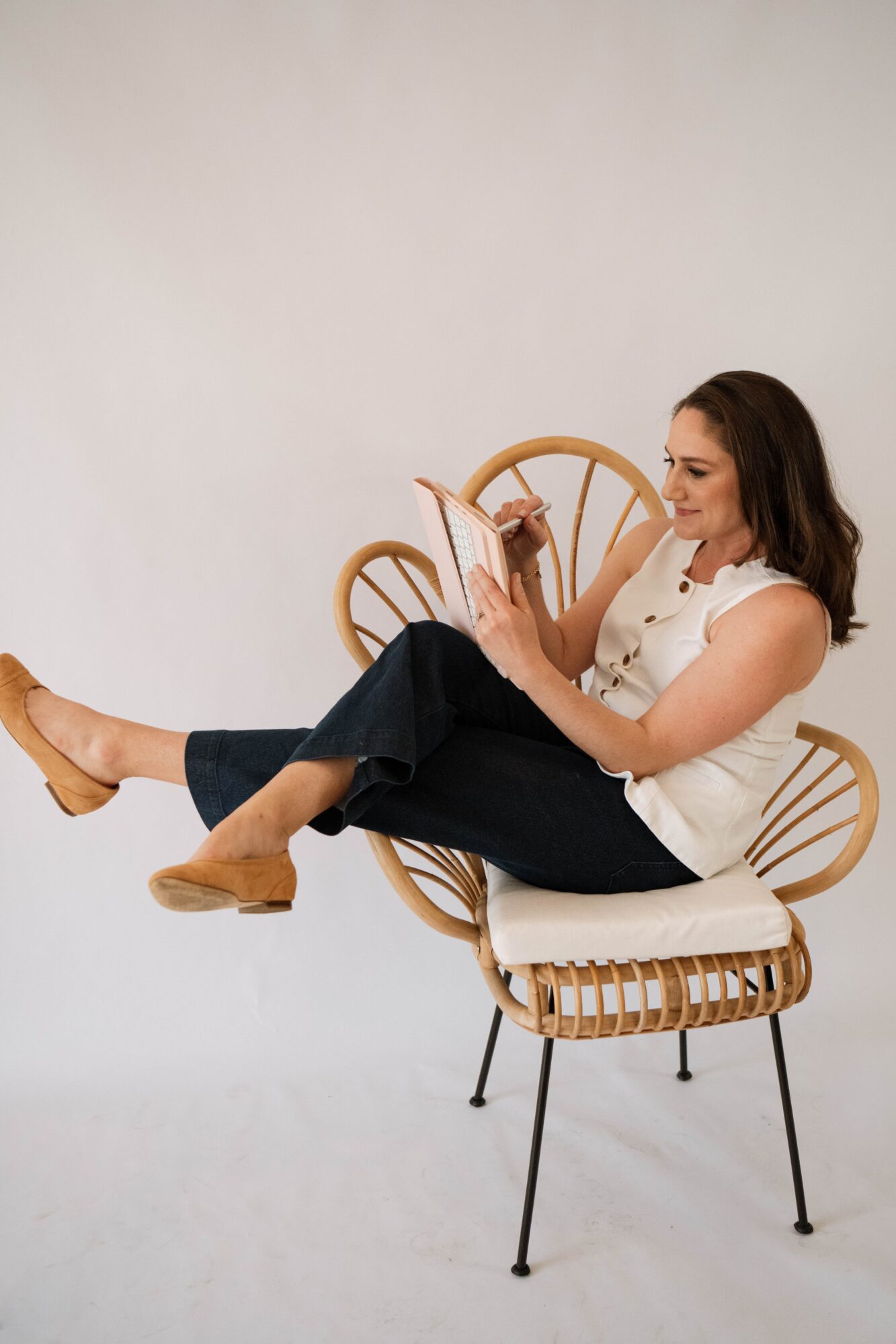 Woman sitting on a modern chair, reading a book, with a plain light background.