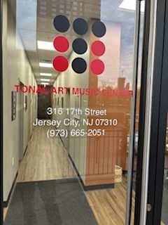 Glass door with red and black dots, text with address and contact info, and a reflection of the street outside.