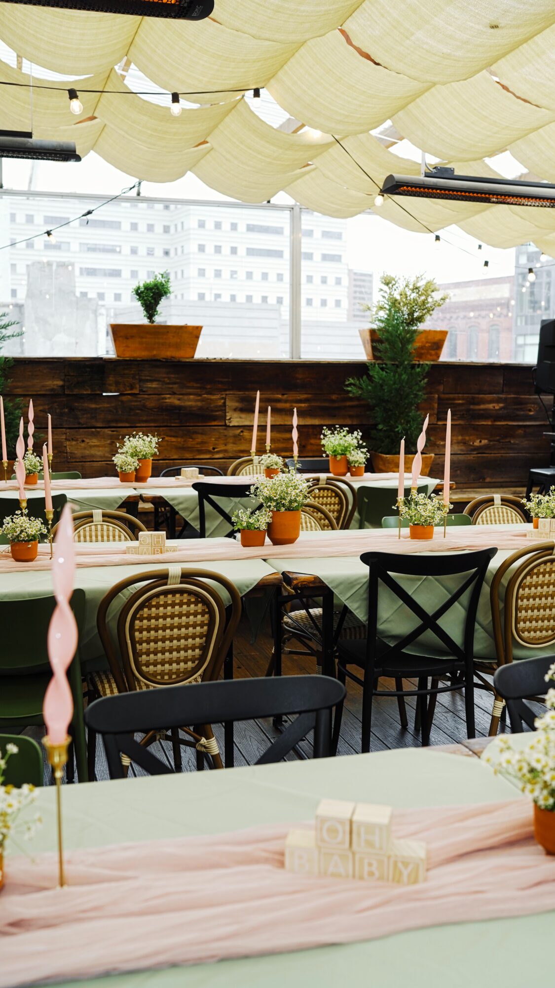 Indoor event space with tables, chairs, and floral decorations, large windows, and ceiling fabric drapes.