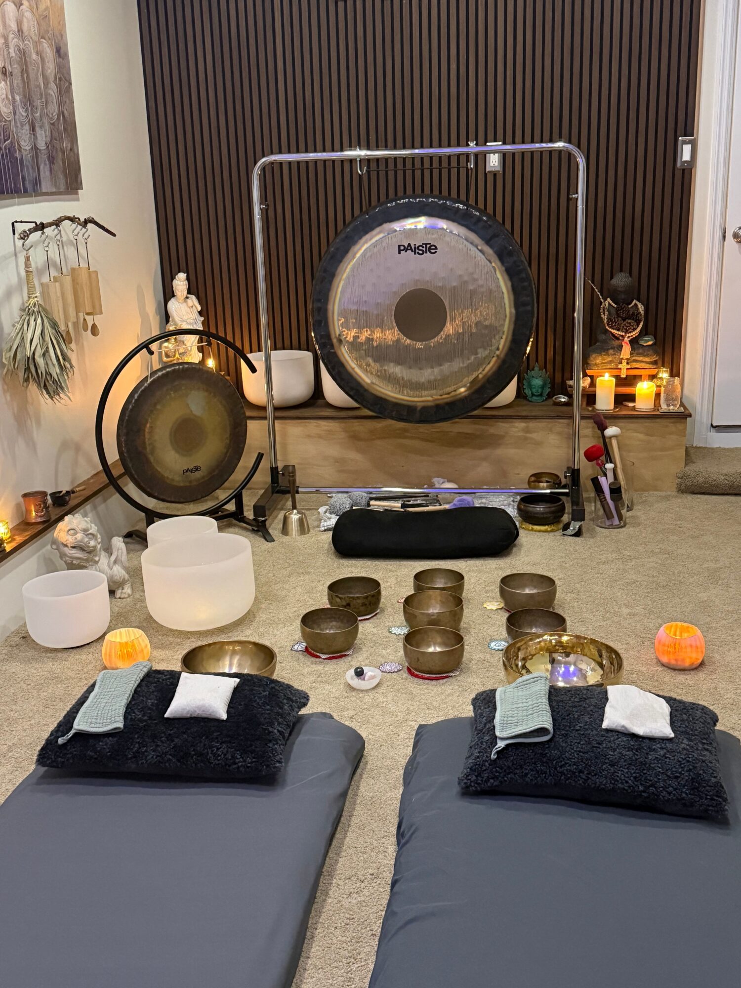 Table setting with black napkins, white plates, and various small decorative items on a table, with a gong and other objects in the background.