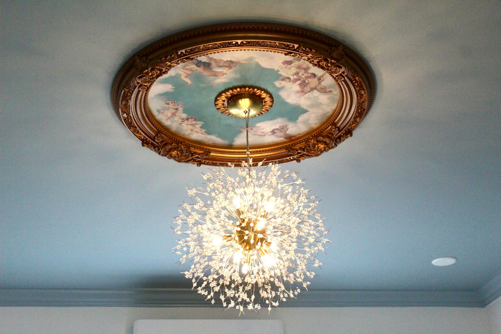 Chandelier hanging from a ceiling with decorative ceiling medallion, viewed upside down.