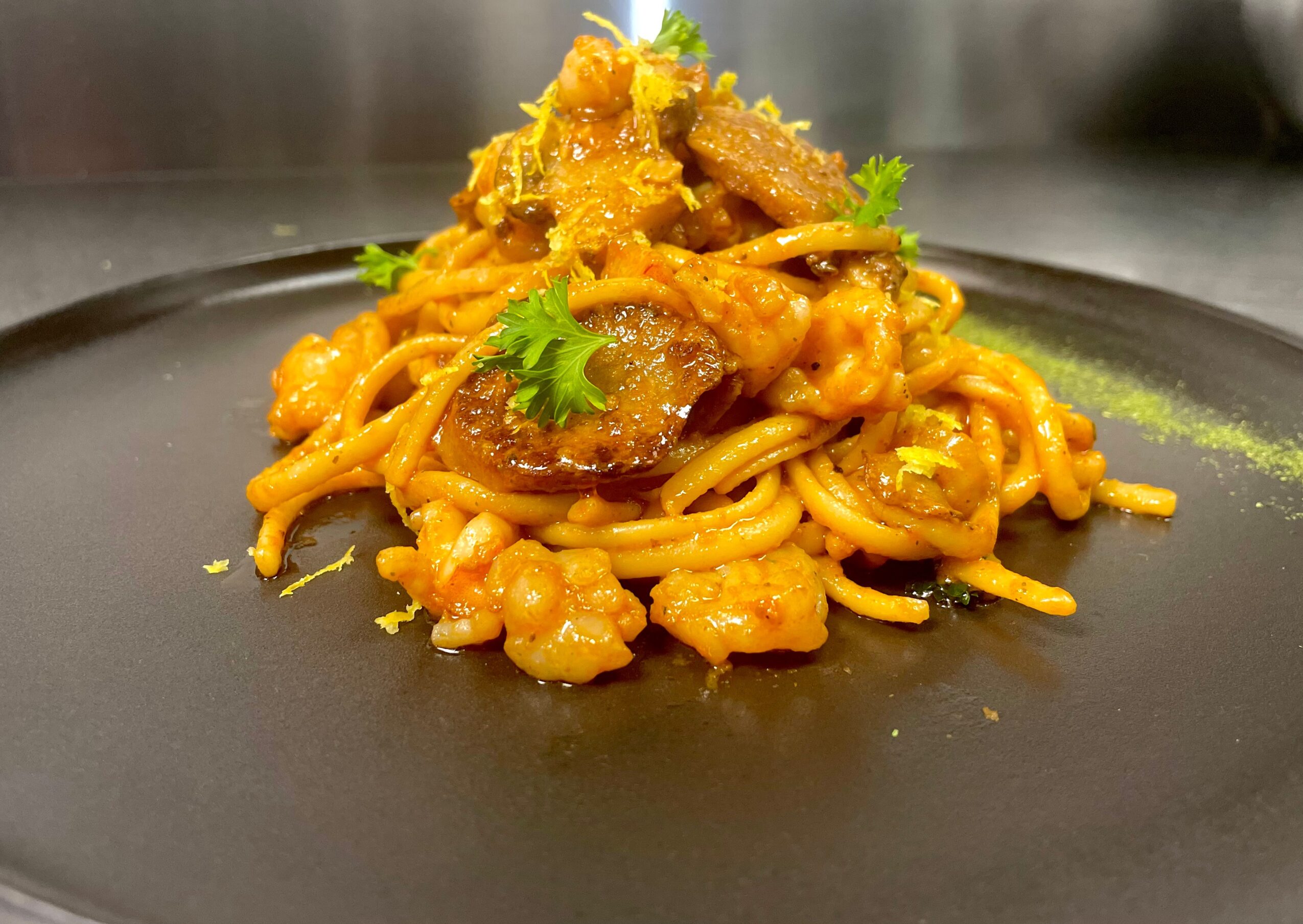 Spaghetti with sauce, garnished with cilantro, served on a black plate.