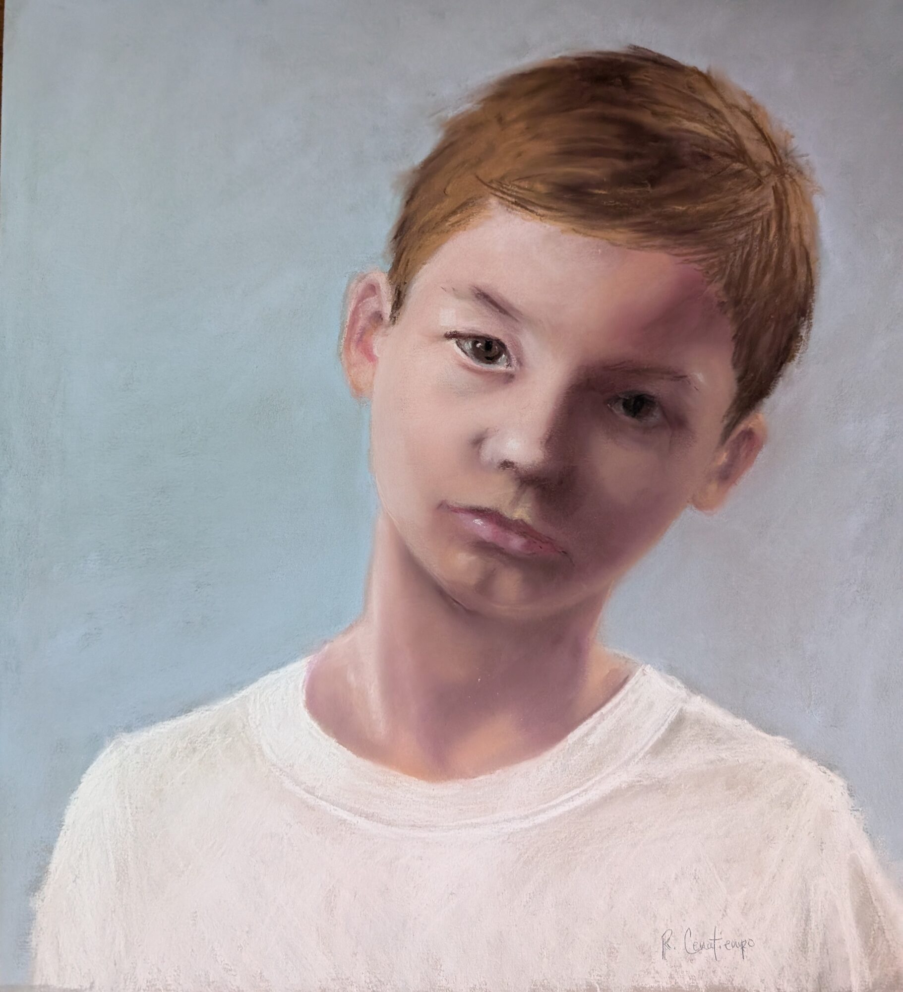 Young boy with red hair and a neutral expression, wearing a white shirt, against a plain background.