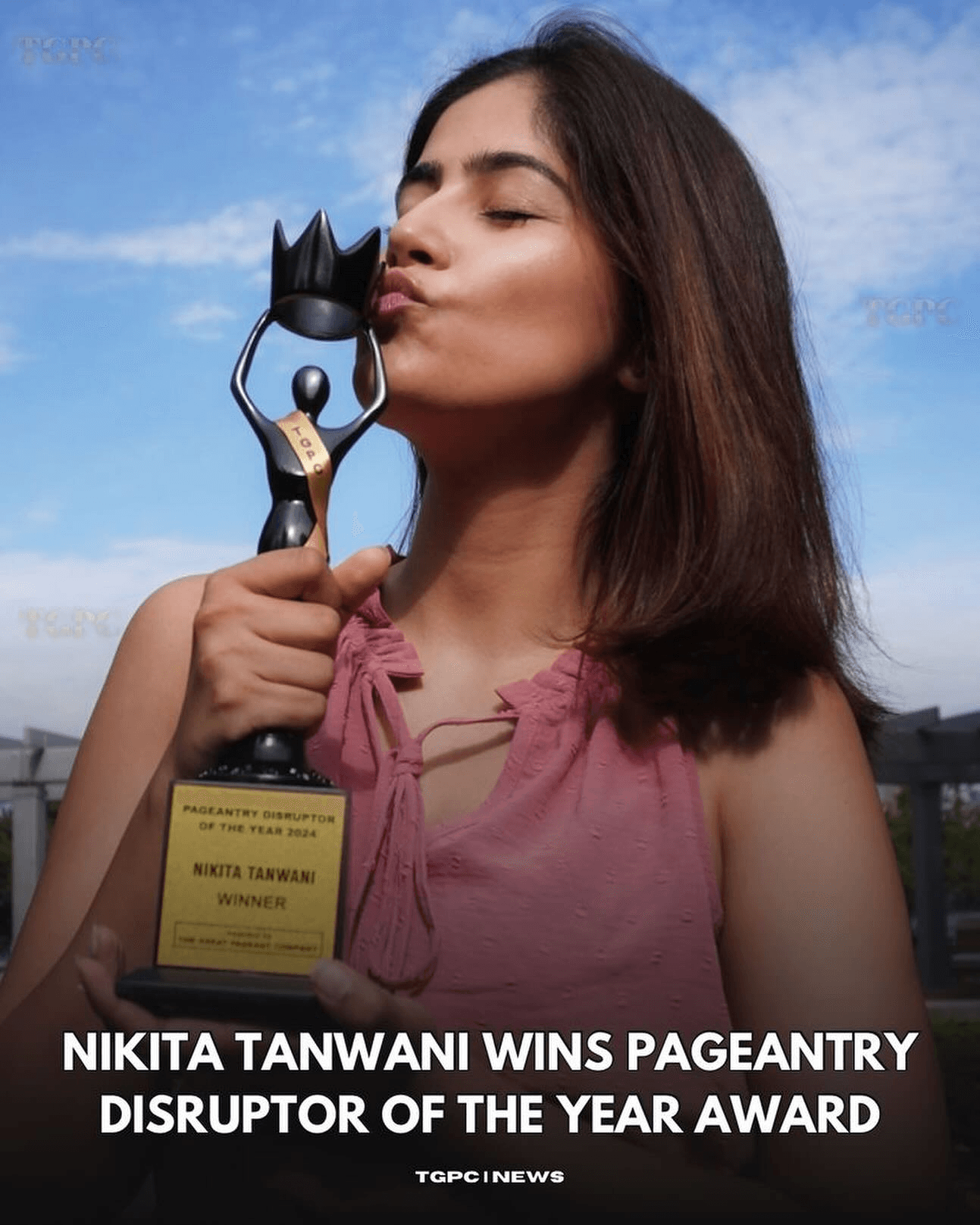 Young woman with shoulder-length hair kisses a trophy shaped like a cat against a blue sky background.