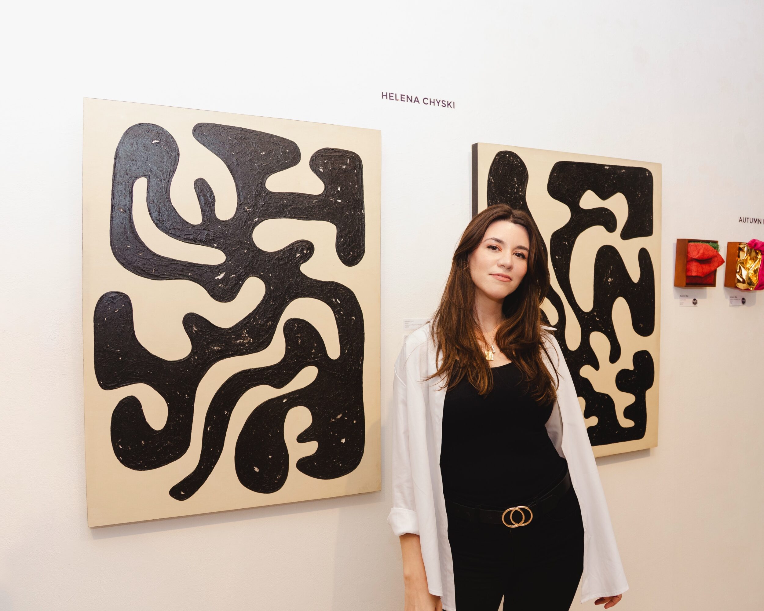 Woman standing in front of abstract black and white artwork at an art gallery.