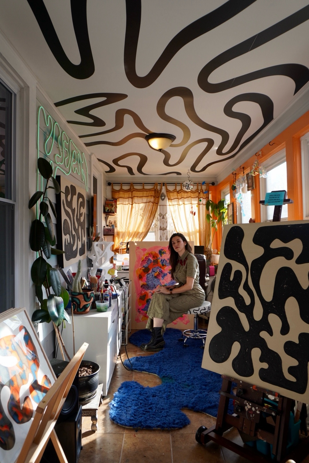 Person sitting on a chair in a colorful, decorated room with abstract black and white ceiling patterns and vibrant decor.