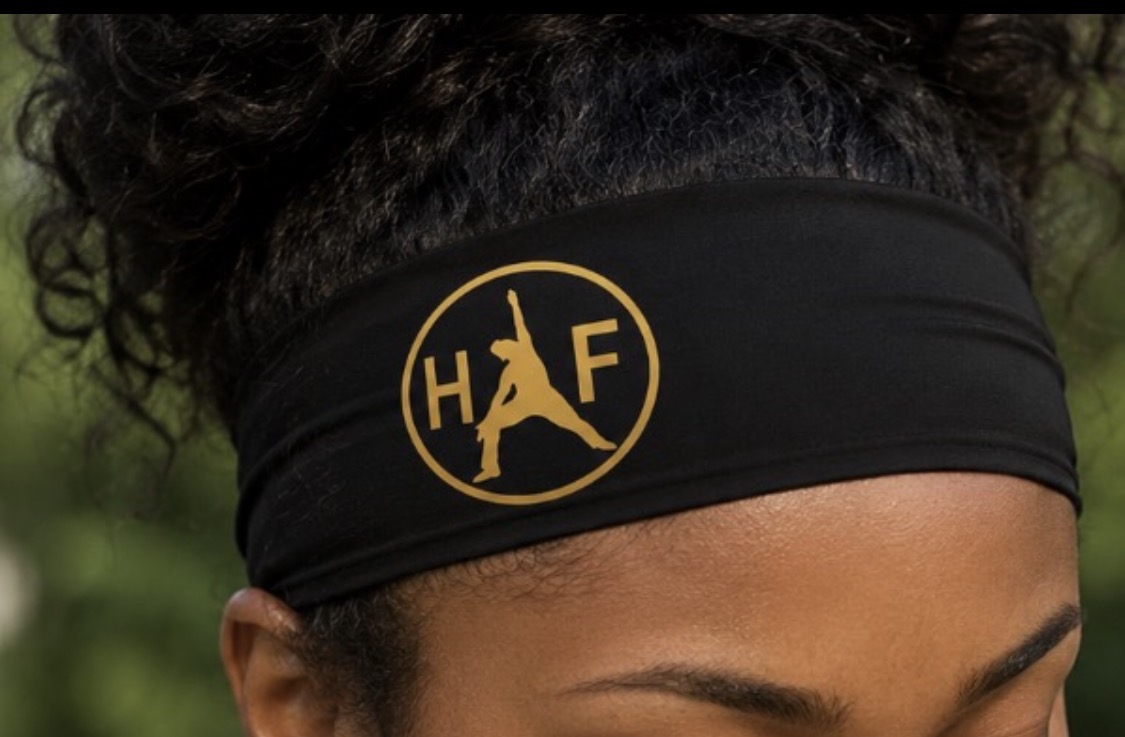 Close-up of a person wearing a black headband with a yellow logo featuring a person jumping and the letters H and F.